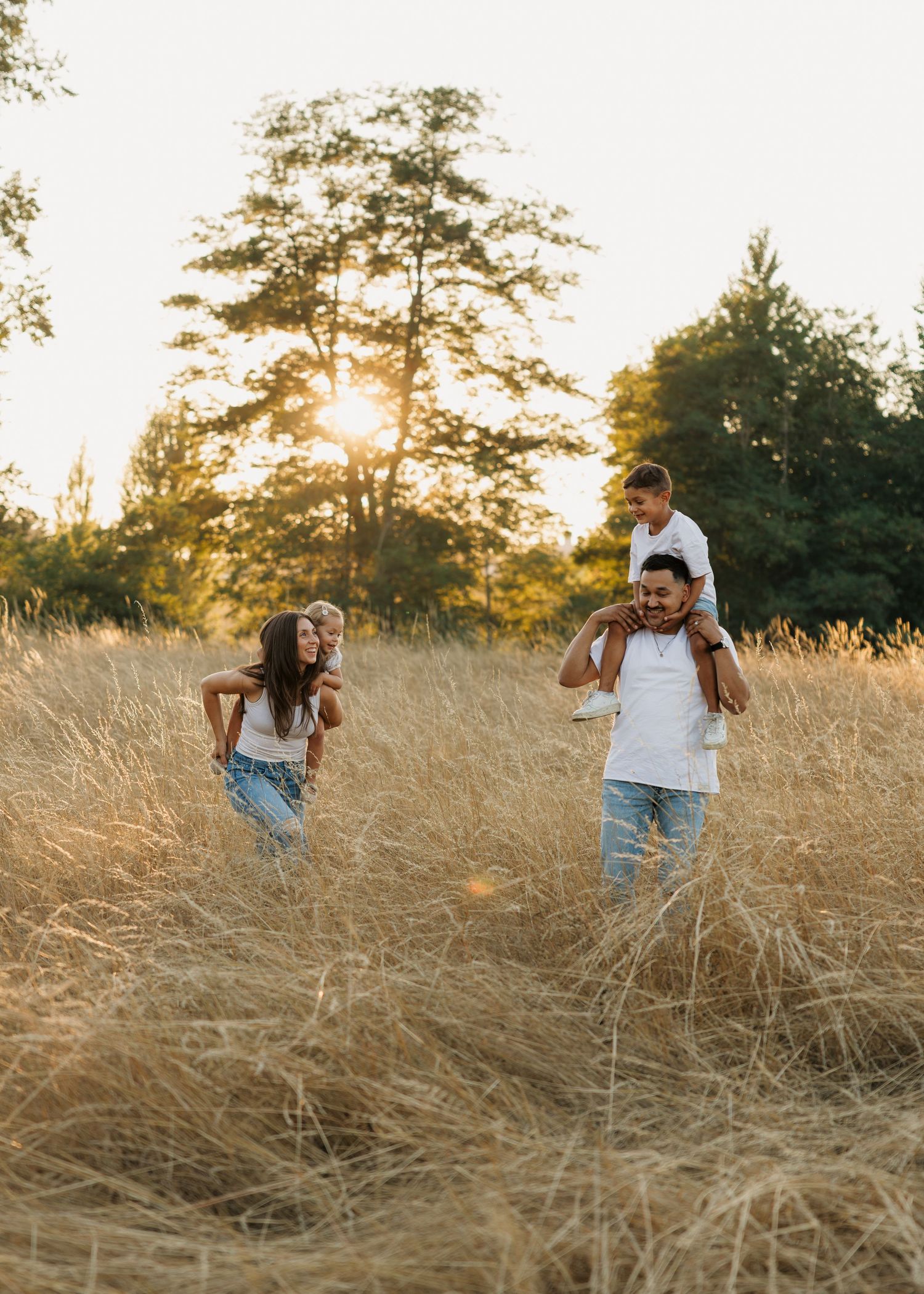 Family walking through a sunlit field at golden hour during an outdoor family photography session in Washington.