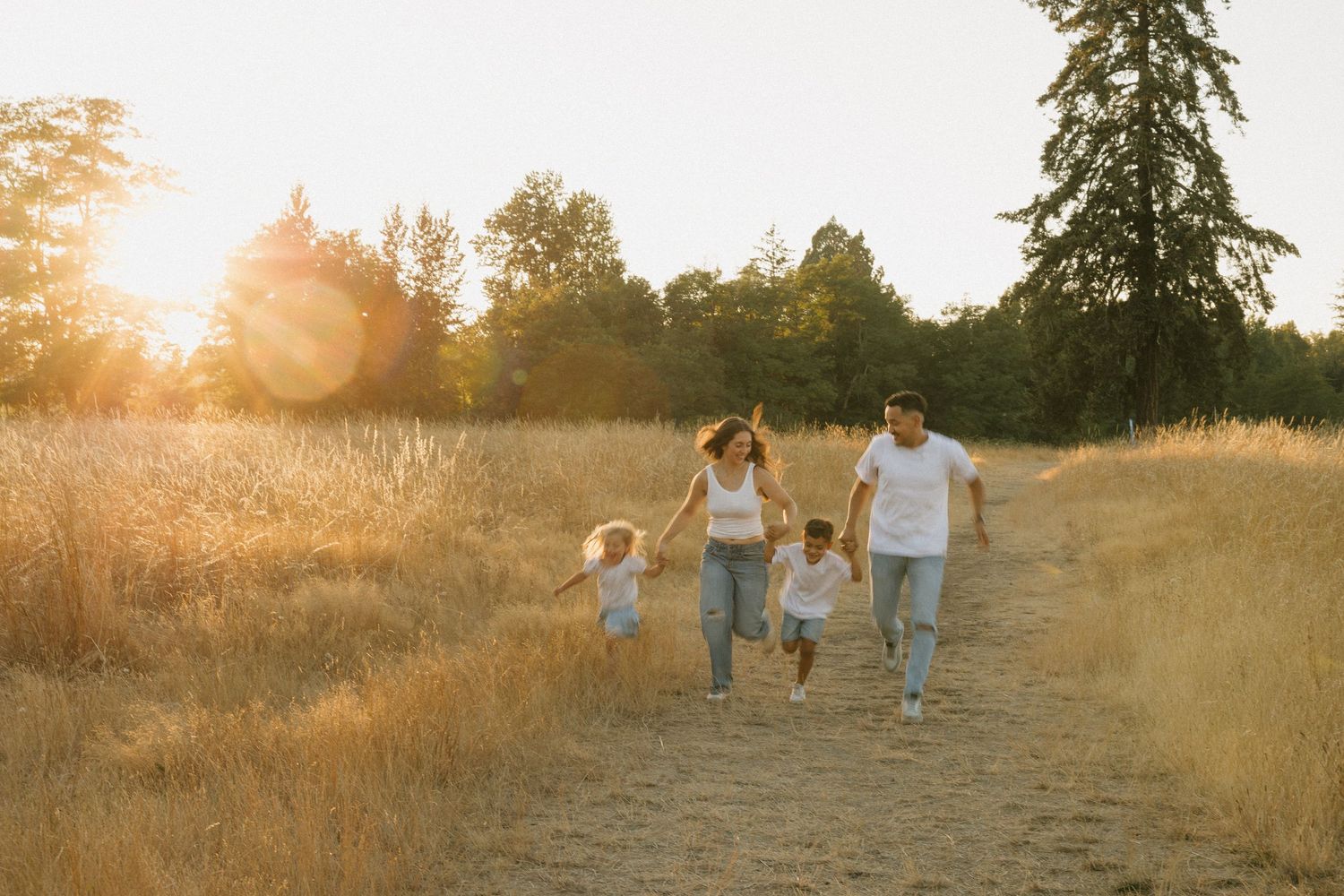 Family running together through a golden field at sunset during a candid Washington family photography session.