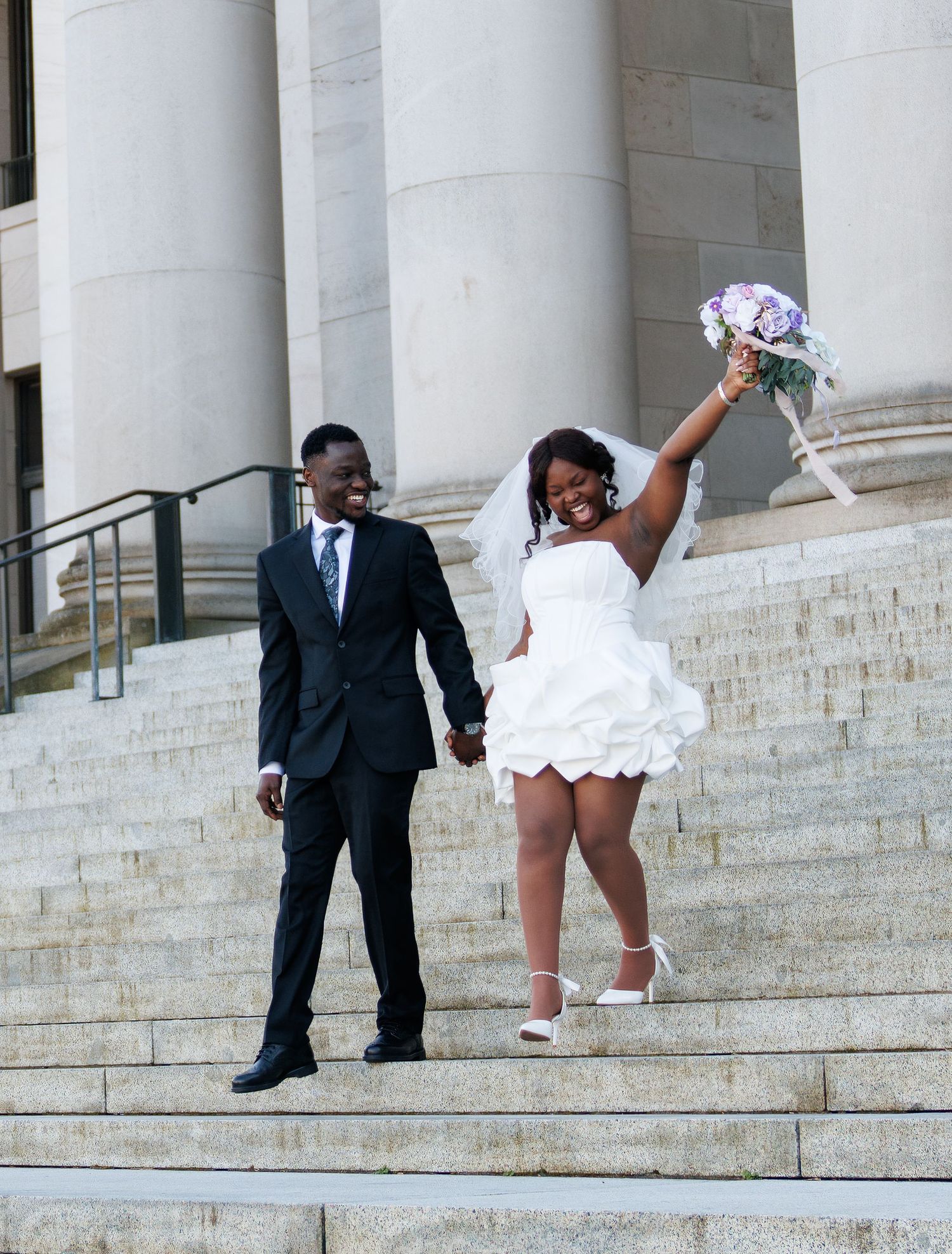 Joyful newlyweds walking down the Washington State Capitol steps after their Olympia wedding