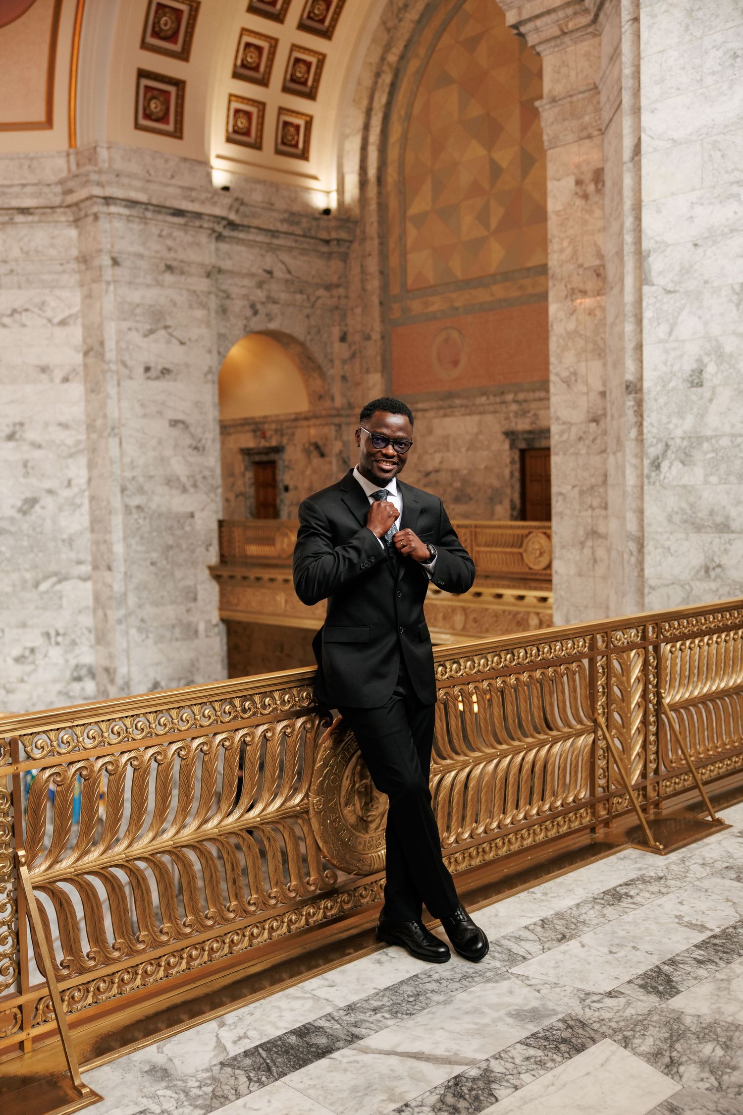 Groom adjusting his tie during wedding portraits inside the Washington State Capitol in Olympia