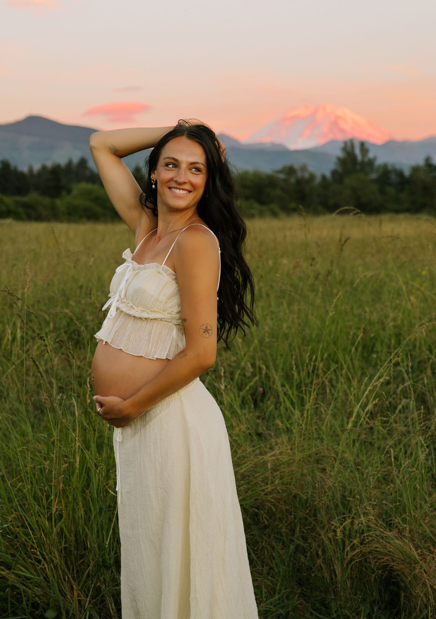 Maternity portrait in a golden field with Mount Rainier glowing at sunset in Washington.
