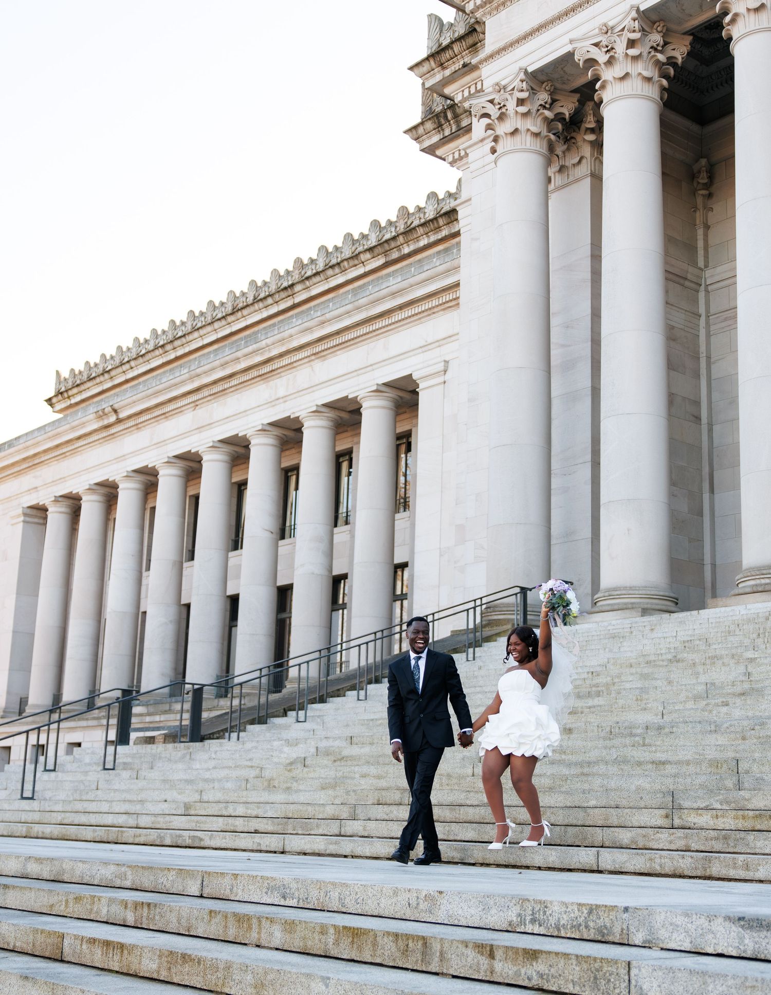 Newlyweds walking together beneath the grand columns of the Washington State Capitol