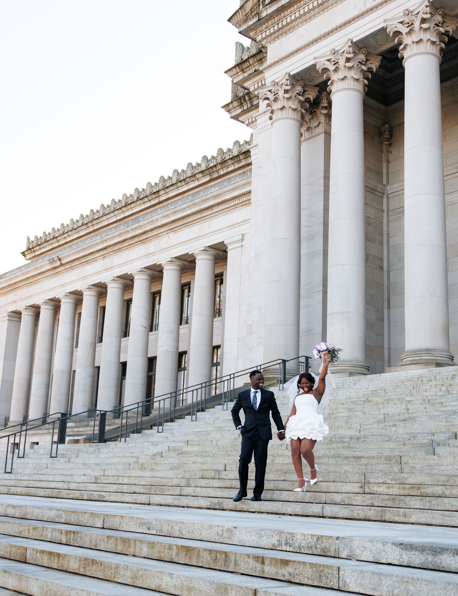 Joyful newlyweds walking hand in hand on the Washington State Capitol steps