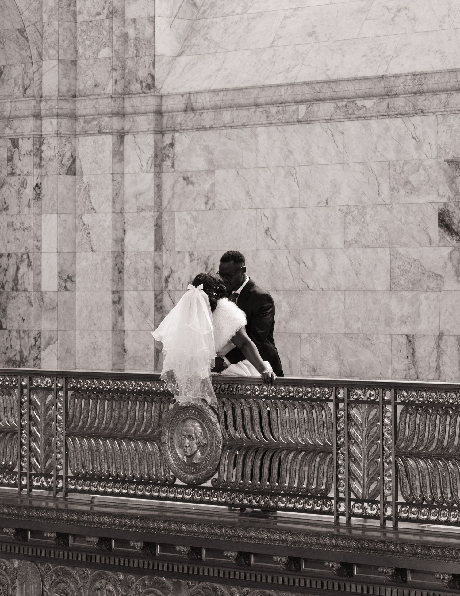 Bride and groom sharing a kiss on a balcony inside the Washington State Capitol