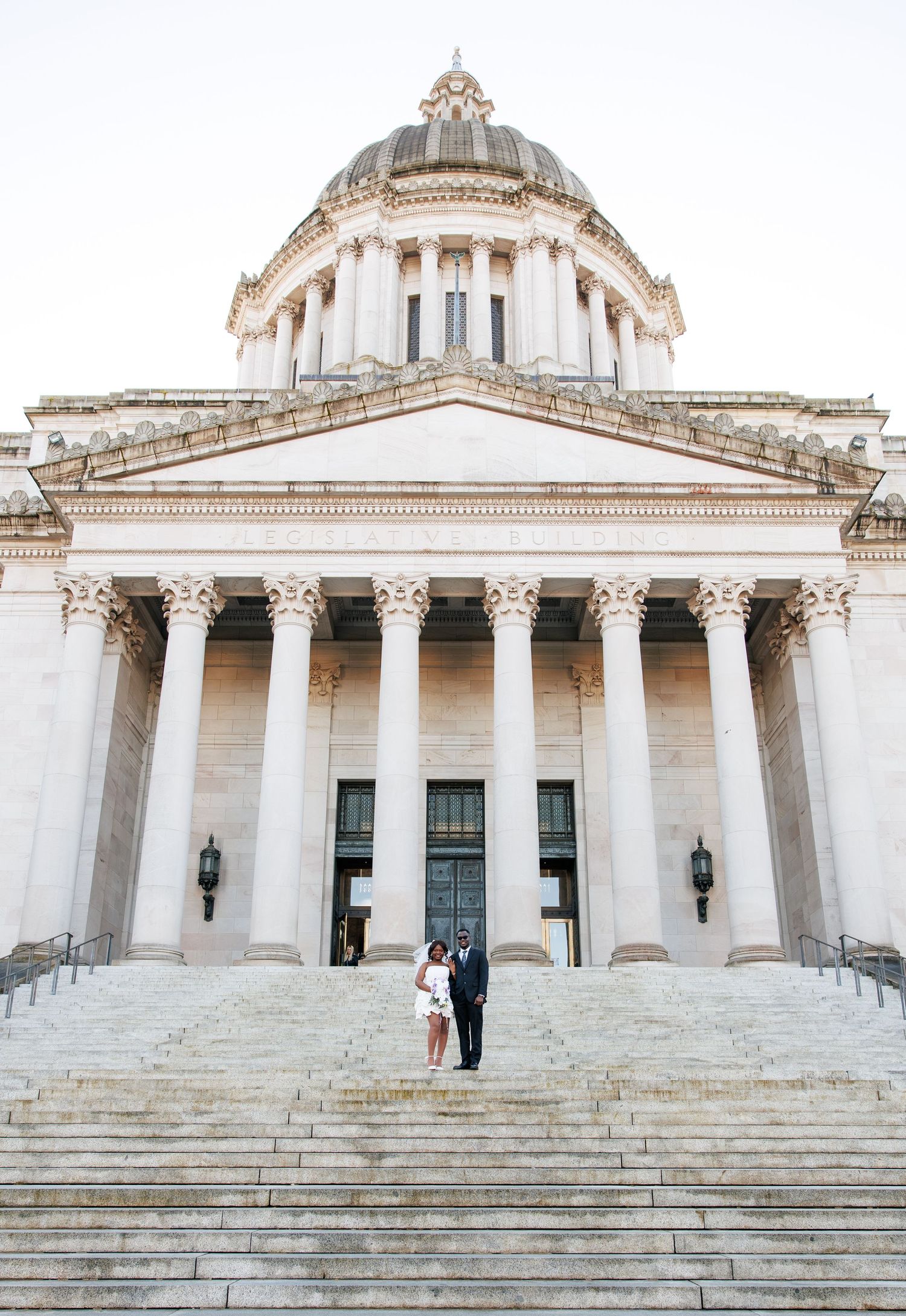 Wide wedding portrait of newlyweds beneath the Washington State Capitol dome in Olympia