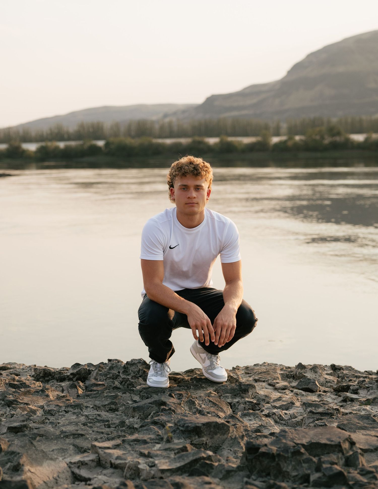 High school senior posing by the water with mountain views during an outdoor Washington senior photography session.