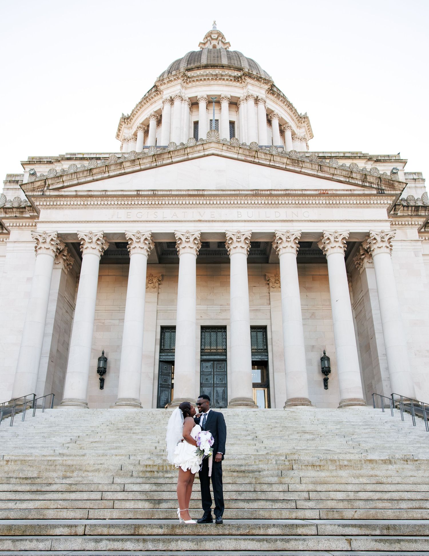Wide wedding portrait of newlyweds in front of the Washington State Capitol in Olympia