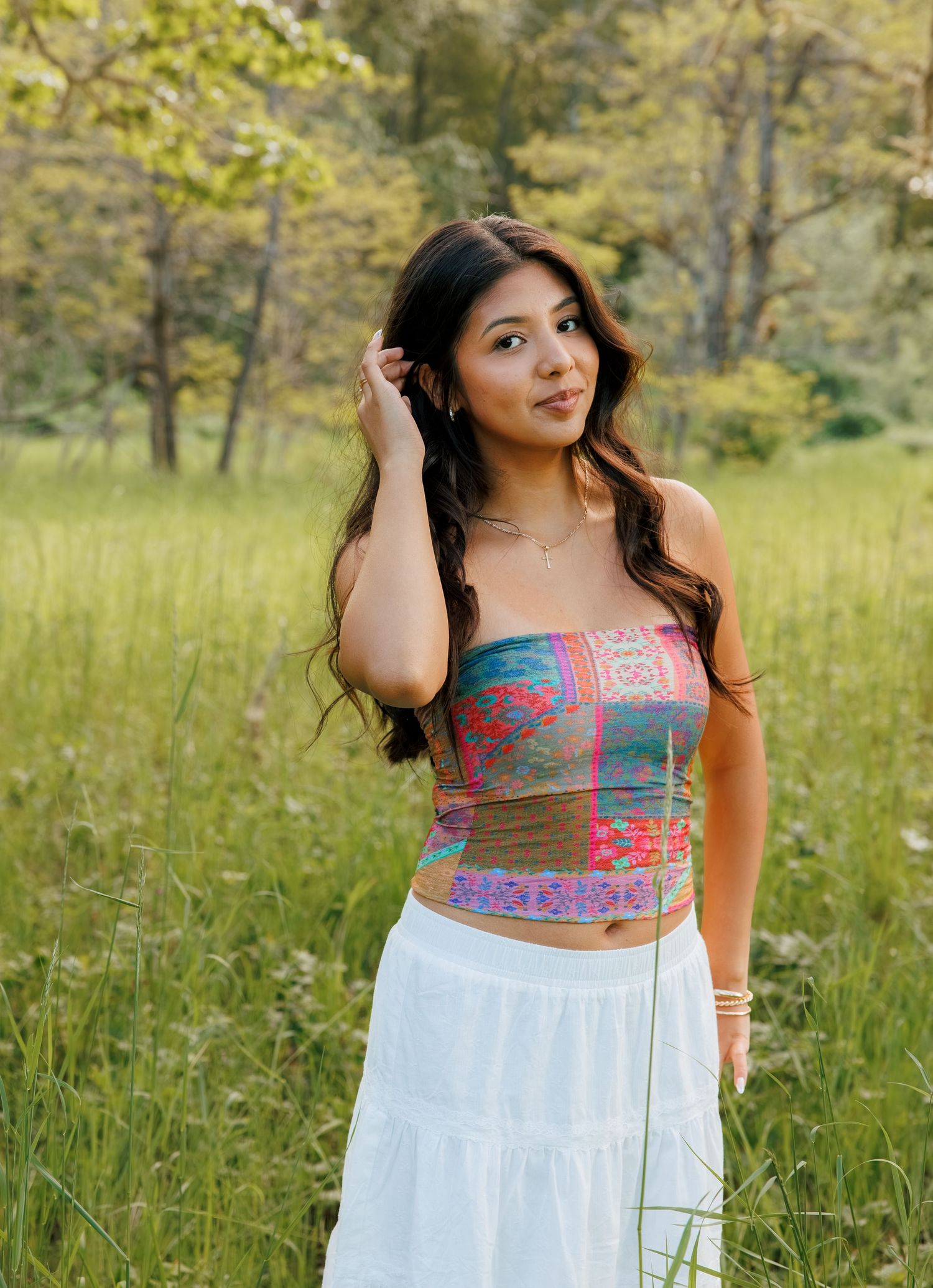 Washington senior portrait in a sunlit field surrounded by soft greenery and trees.