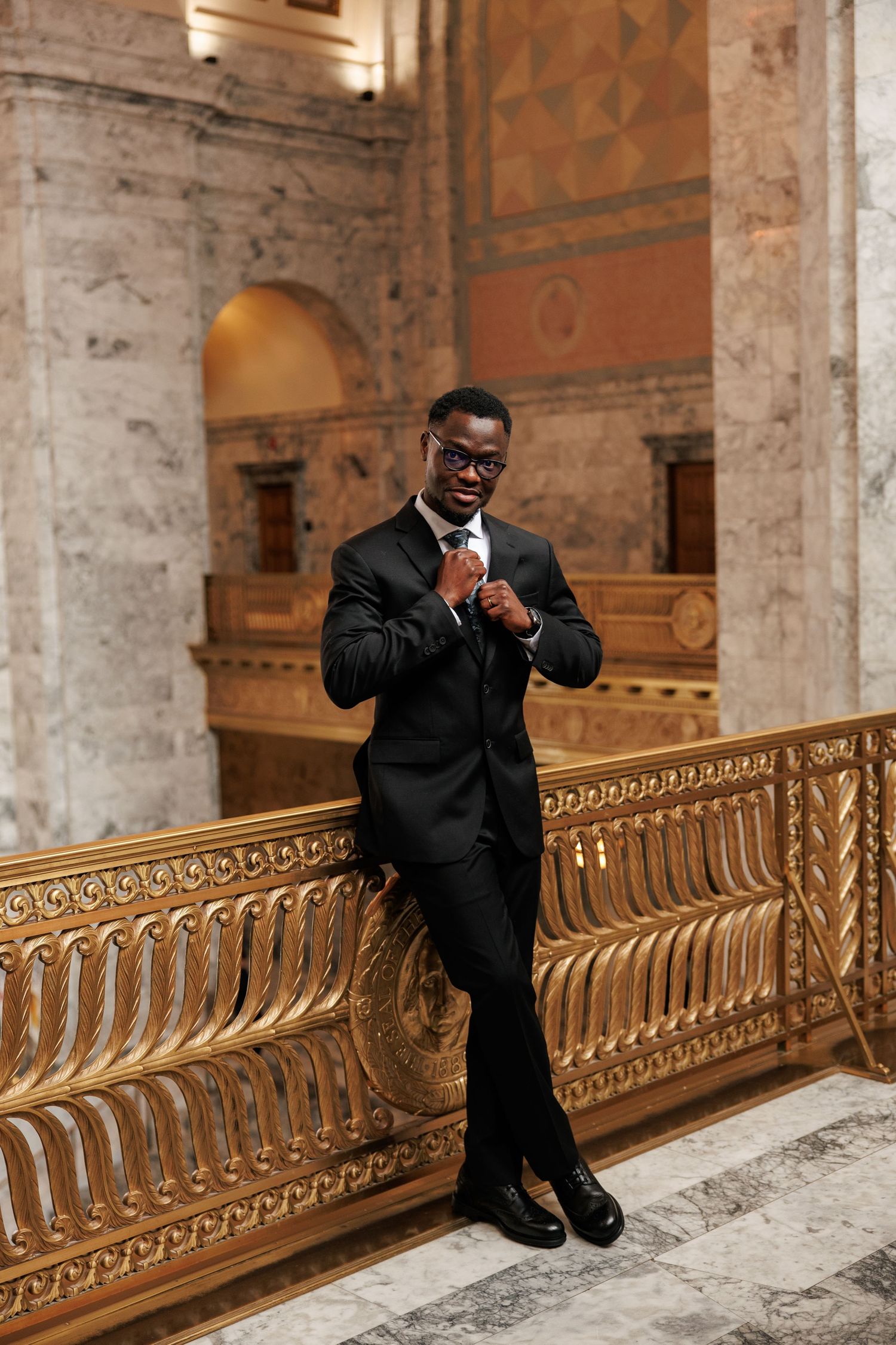 Groom adjusting his tie during his wedding portrait inside the Washington State Capitol in Olympia