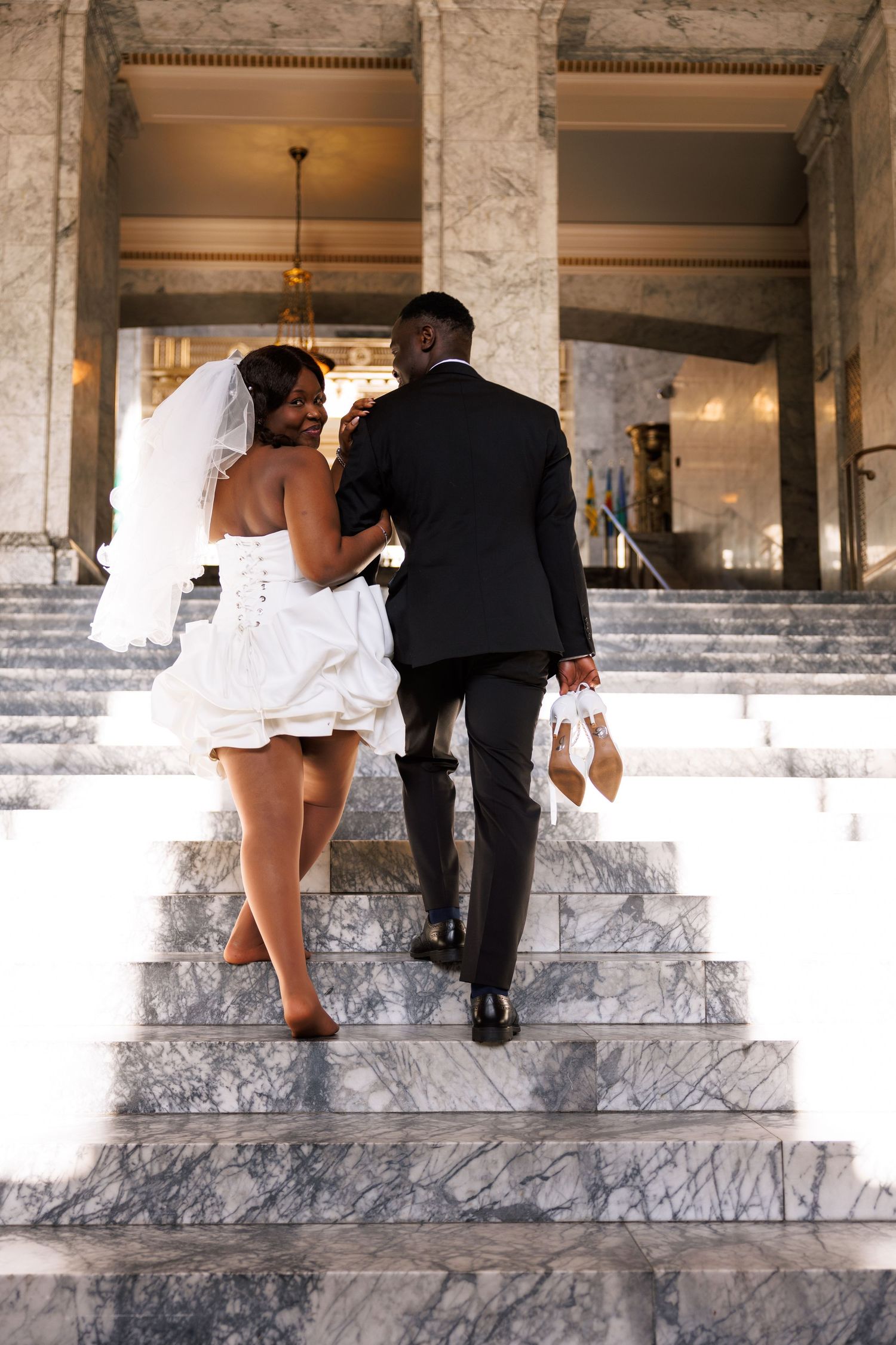 Newlyweds walking hand in hand up the marble stairs inside the Washington State Capitol