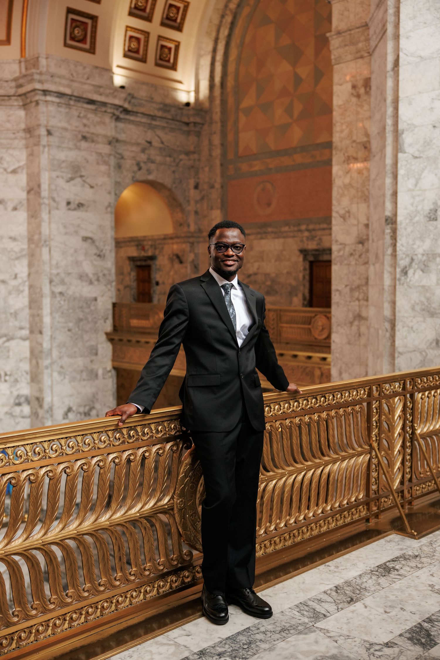 Groom smiling beside the ornate railing inside the Washington State Capitol in Olympia