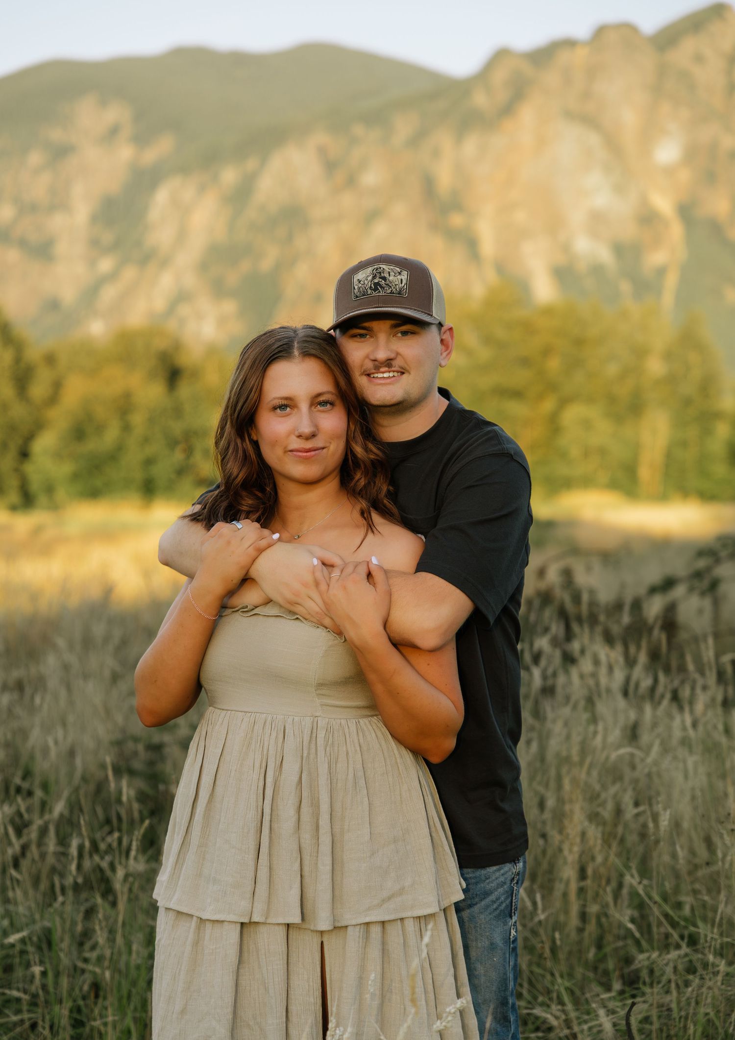 Couple posing together in a sunlit field during a romantic mountain photography session in Washington.
