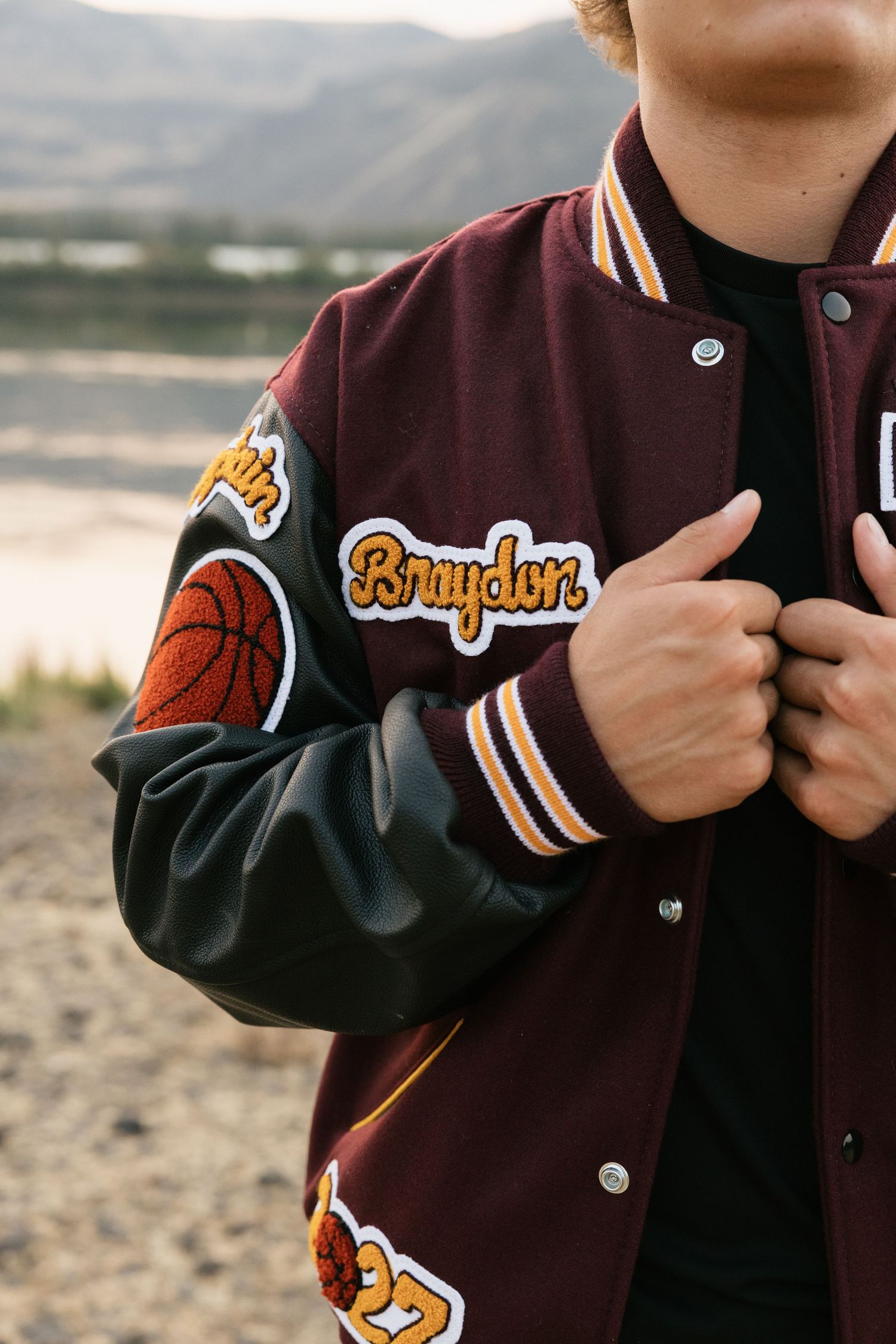 Close-up detail of a varsity letterman jacket featuring basketball patches during a high school senior session.