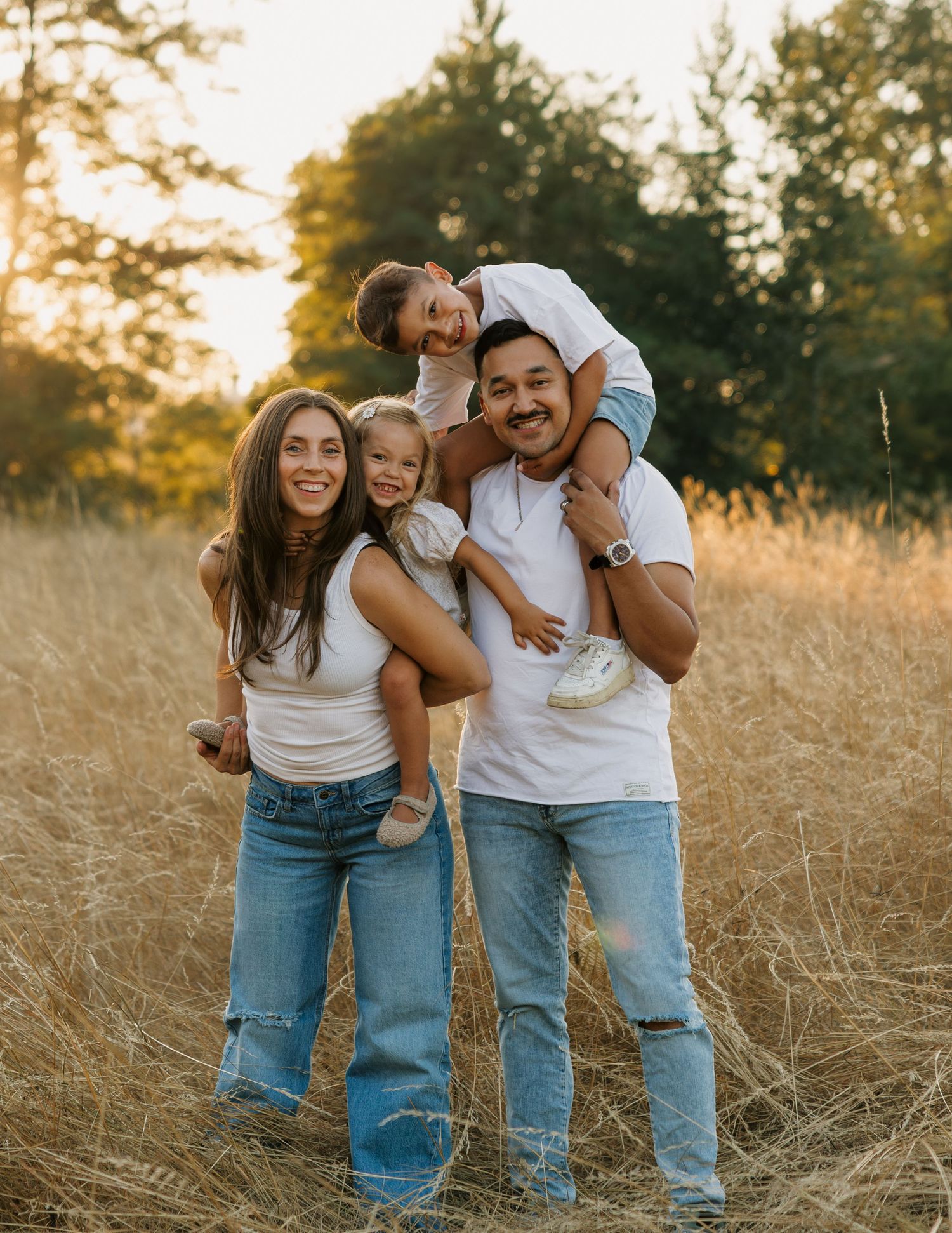 Family laughing together in a golden field during a candid outdoor family photography session in Washington.
