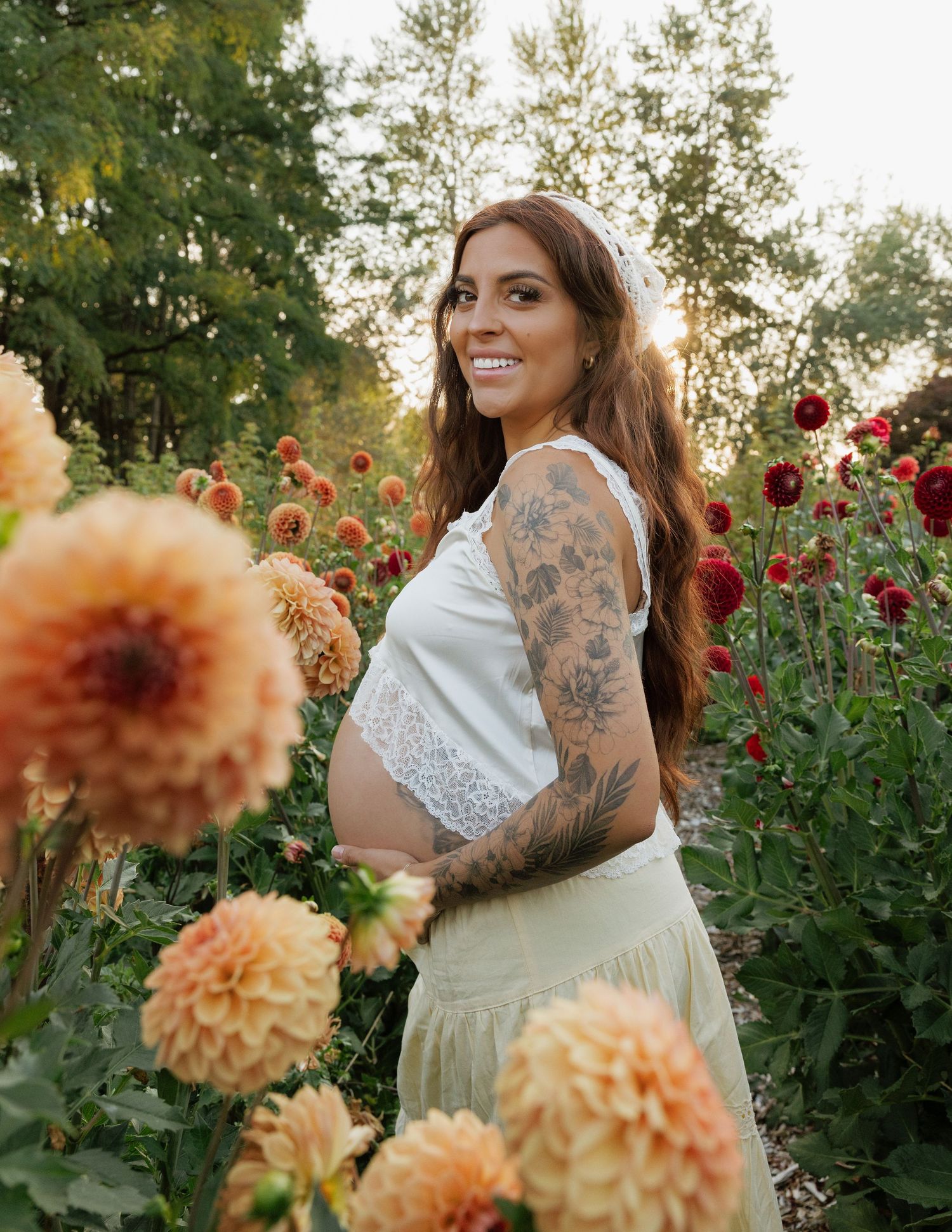 Expecting mother surrounded by colorful flowers during a warm outdoor maternity photography session in Washington.