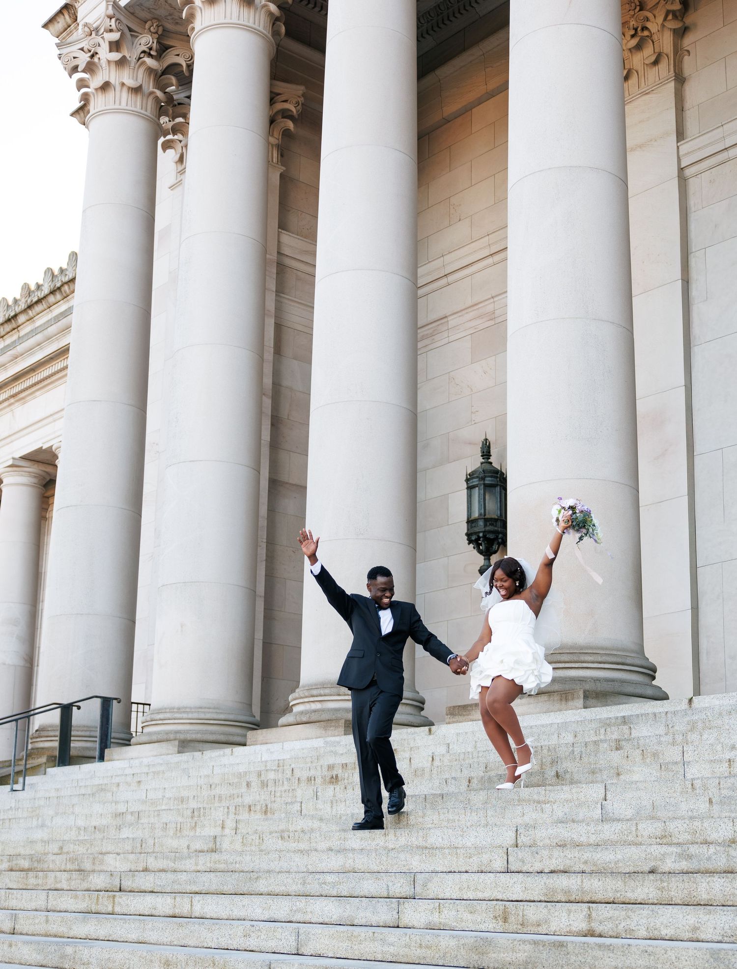 Bride and groom joyfully running down the Washington State Capitol steps after their wedding