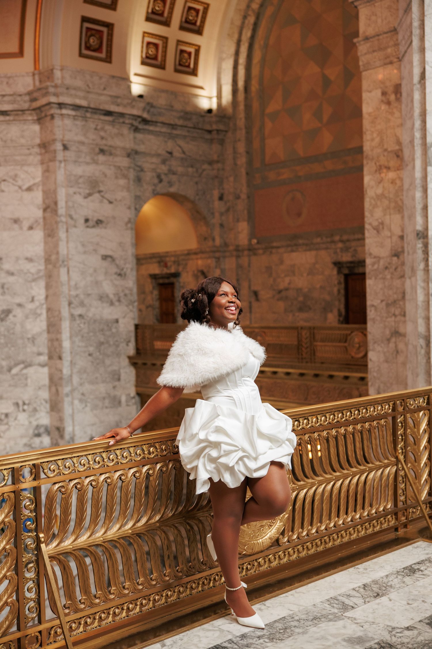 Playful bridal portrait beside the ornate railing inside the Washington State Capitol