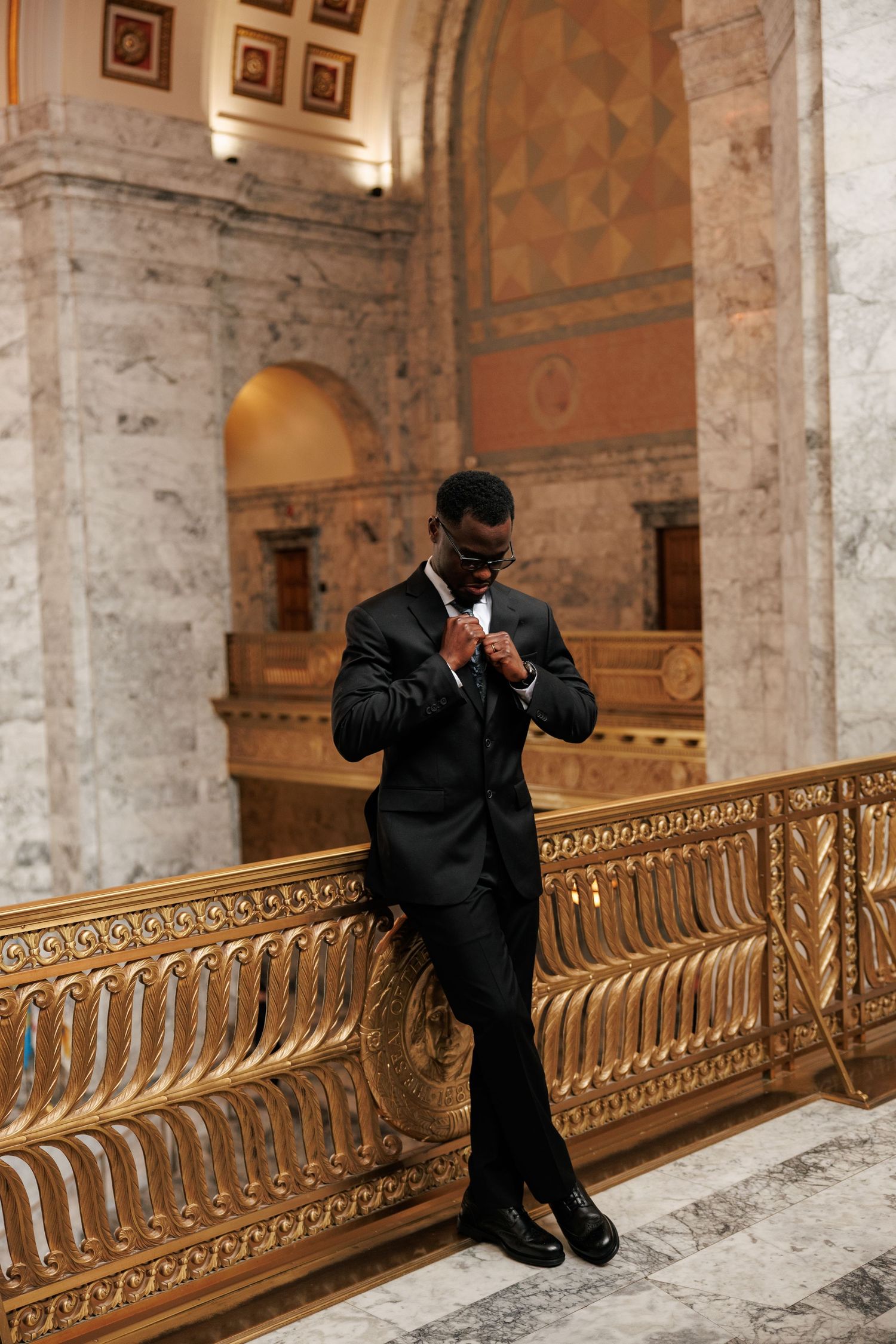 Candid groom portrait adjusting his tie inside the Washington State Capitol