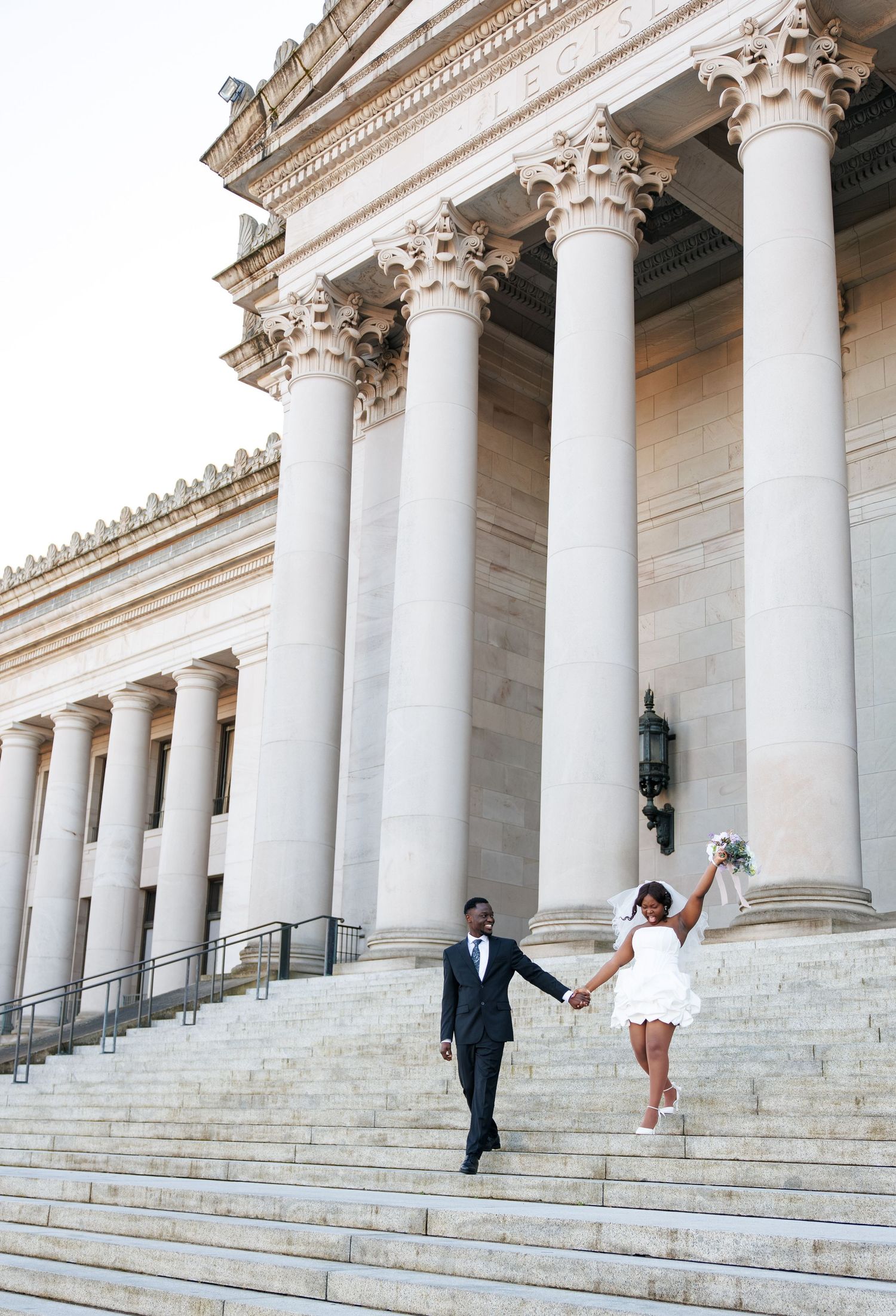 Bride and groom running hand in hand down the Washington State Capitol steps