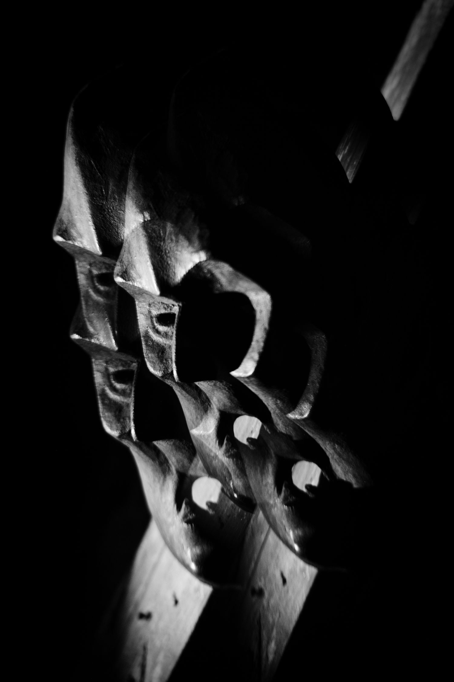 Close-up black and white photo of intricate carved wooden sculpture with dramatic shadows and light.
