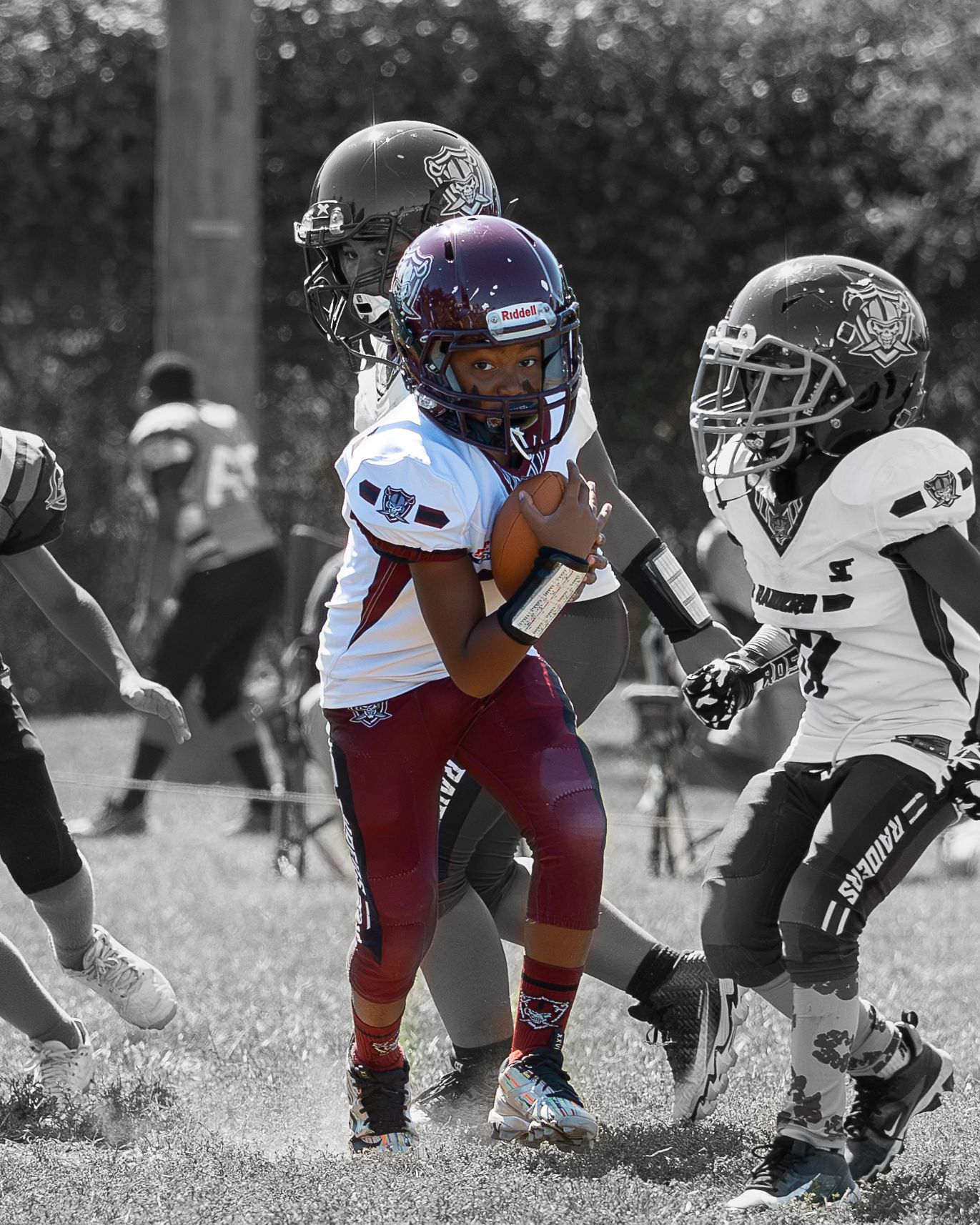 Black and white photo with football player in color, ball in hand running to make a touchdown.