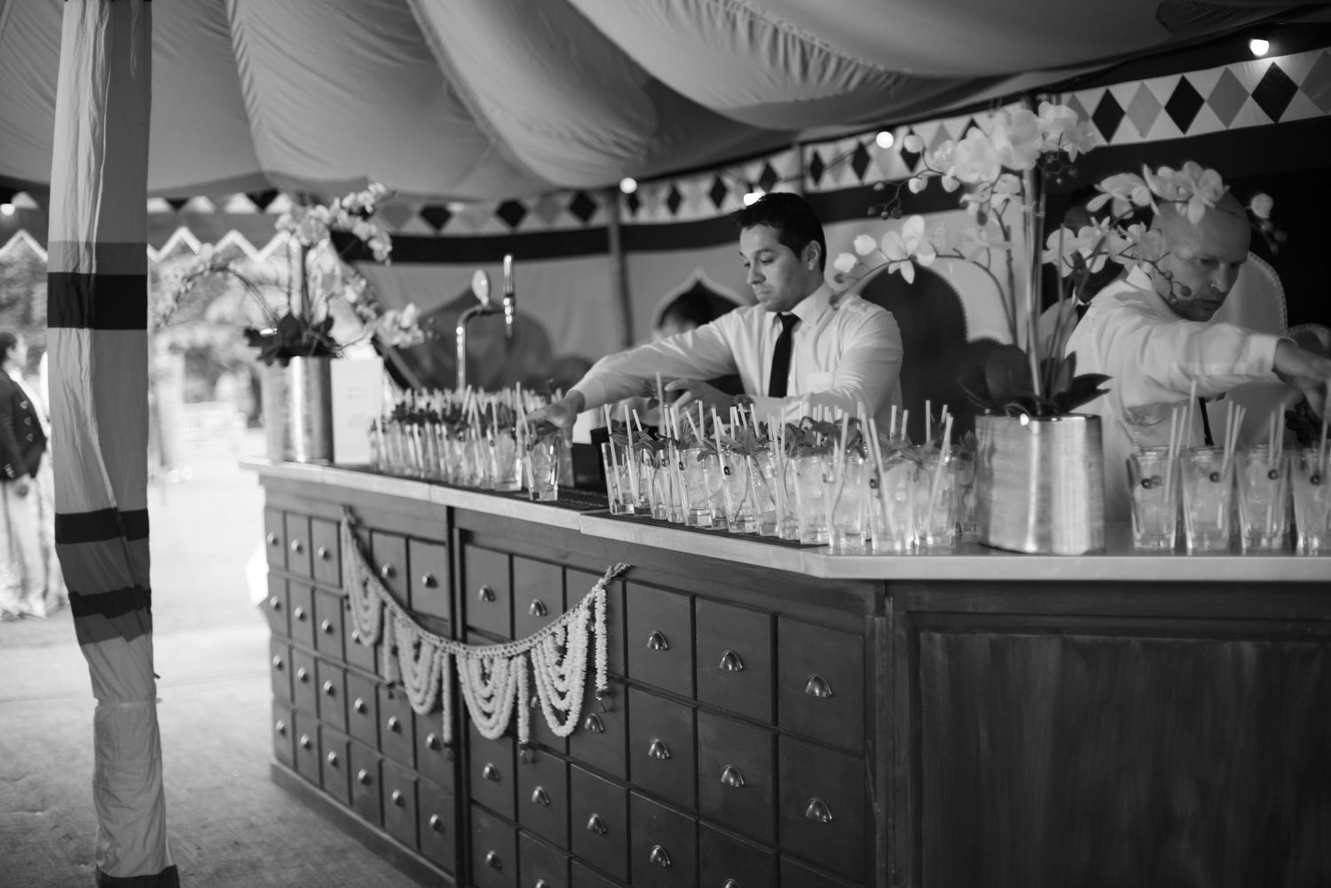 Black and white photo of bartenders serving champagne at an elegant wedding bar.