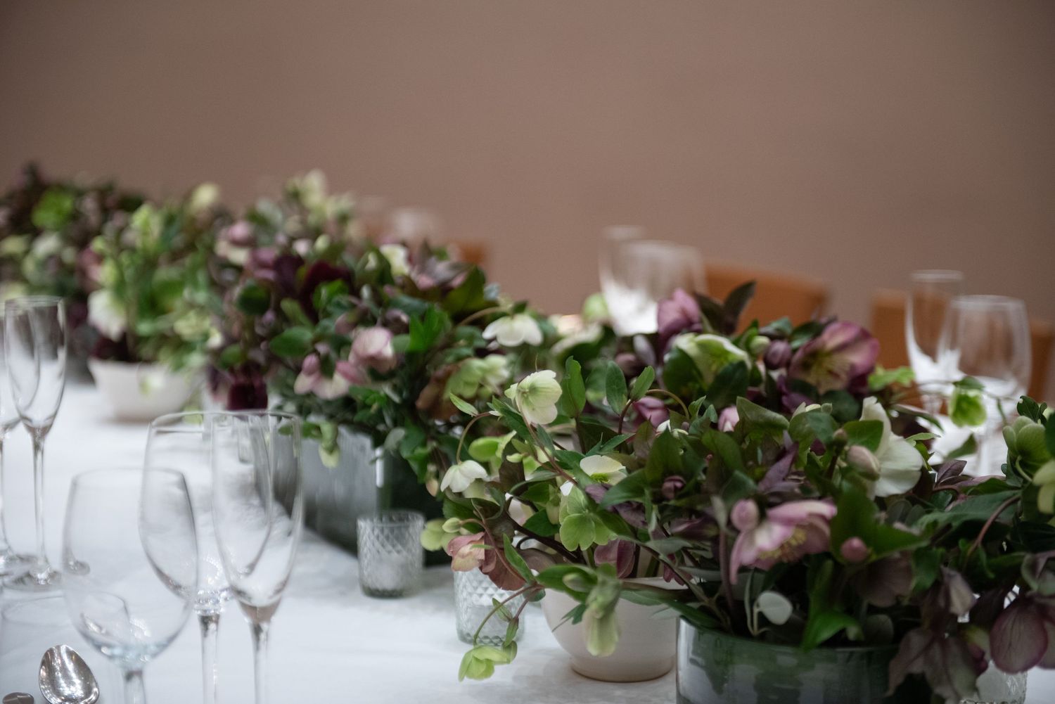 Elegant wedding table setting with lush green and purple floral centerpieces and crystal champagne glasses. Private dining at Cowarth Park