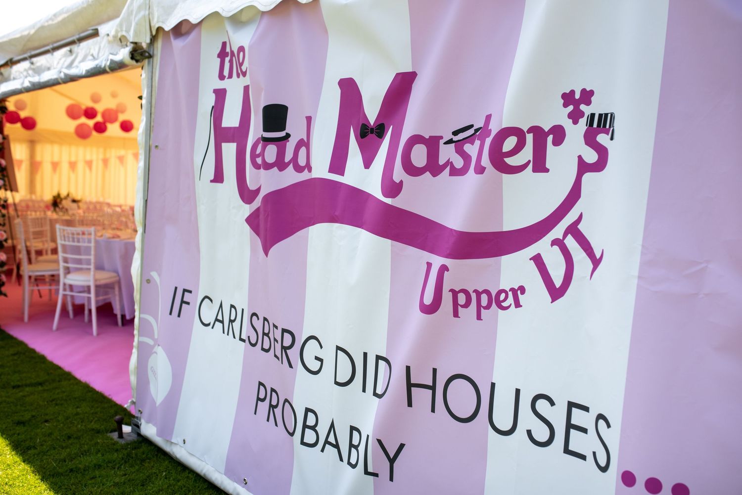 Pink and white banner reading The Head Masters Upper VI with humorous Carlsberg slogan at event.  Leavers lunch at Harrow School