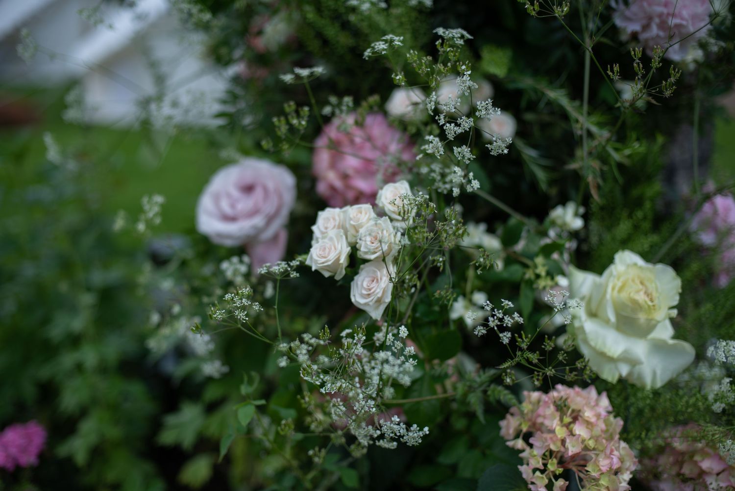 Romantic wedding floral arrangement featuring white and pink roses with lush greenery and hydrangeas.