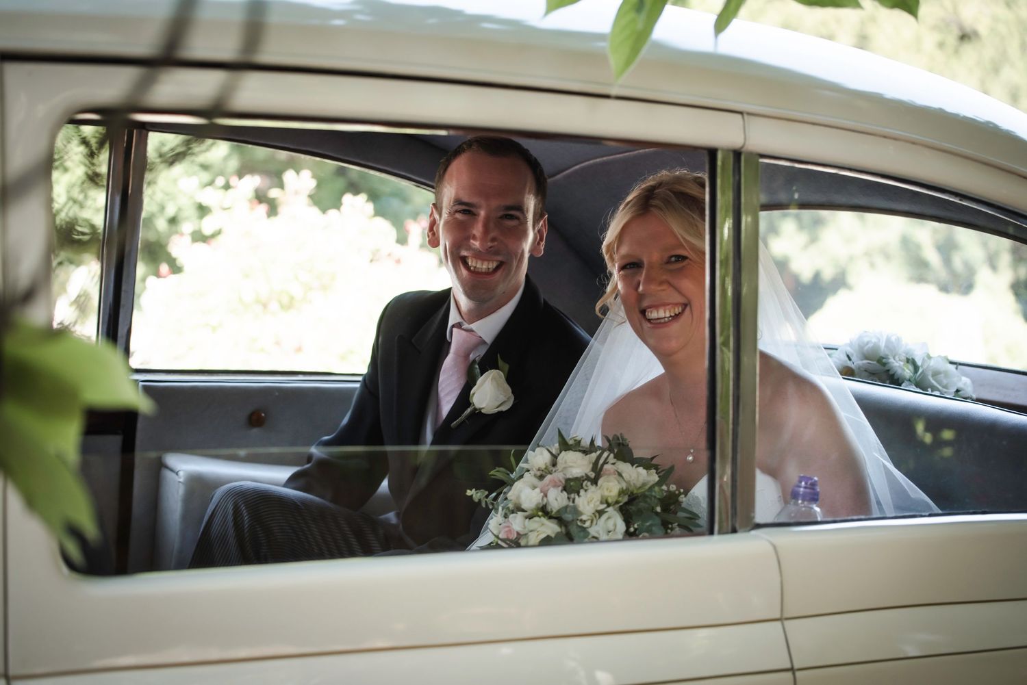 Happy bride and groom smiling through vintage wedding car window after church ceremony. St Michaels Church Bray