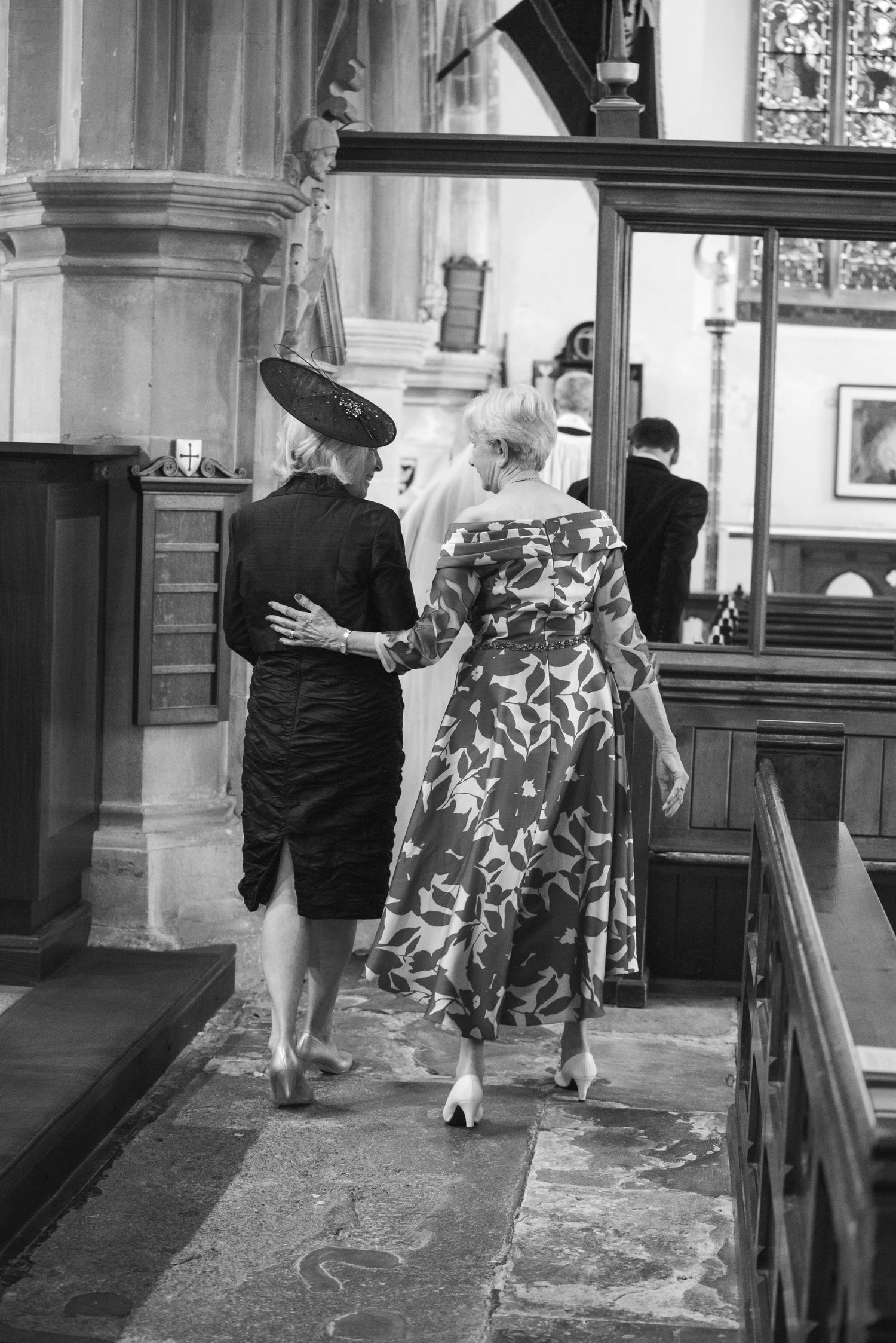 Two elegantly dressed women walking through historic church interior during wedding celebration. St Michaels Church, Bray