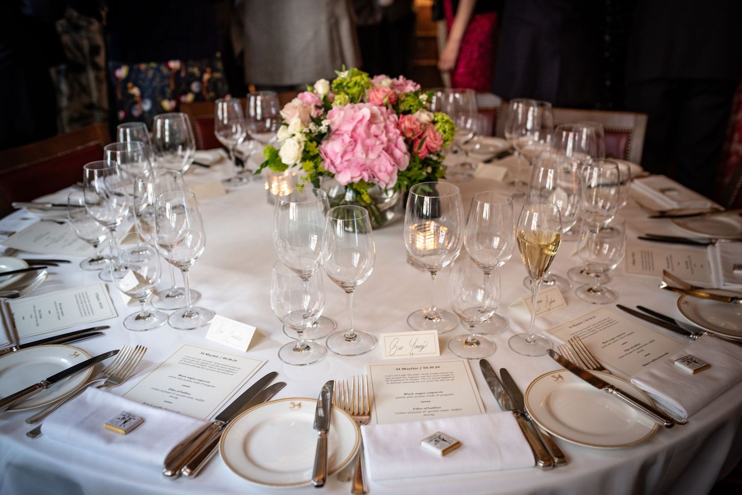 Elegant wedding reception table set with crystal glasses, silverware, and pink floral centerpiece.