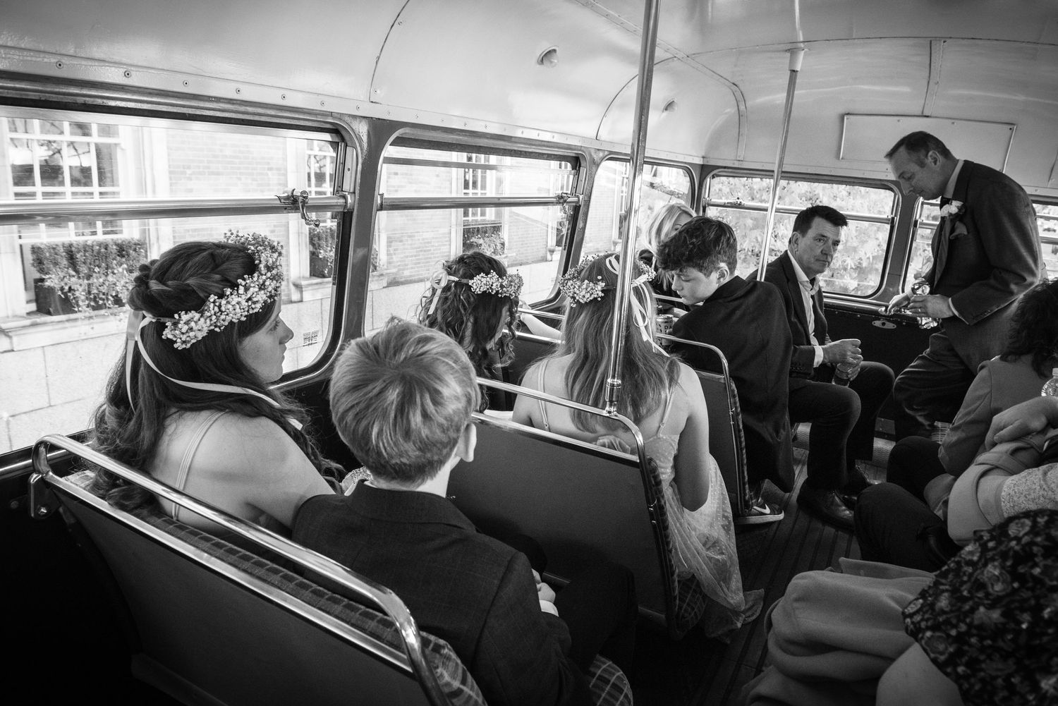 Wedding guests seated inside vintage double-decker bus in black and white photography.
London wedding.