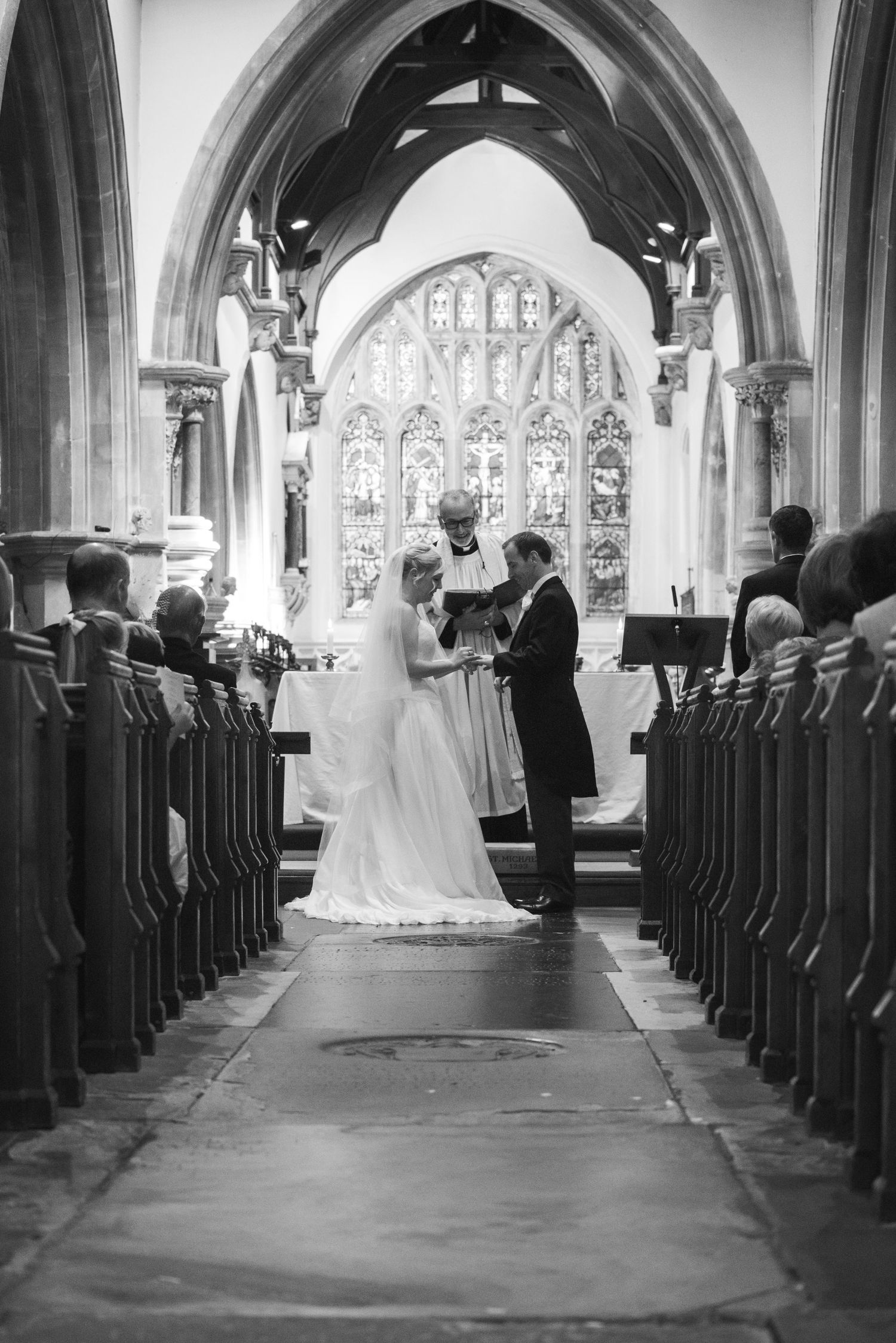 Bride and groom exchange vows at church altar with gothic arches in black and white.