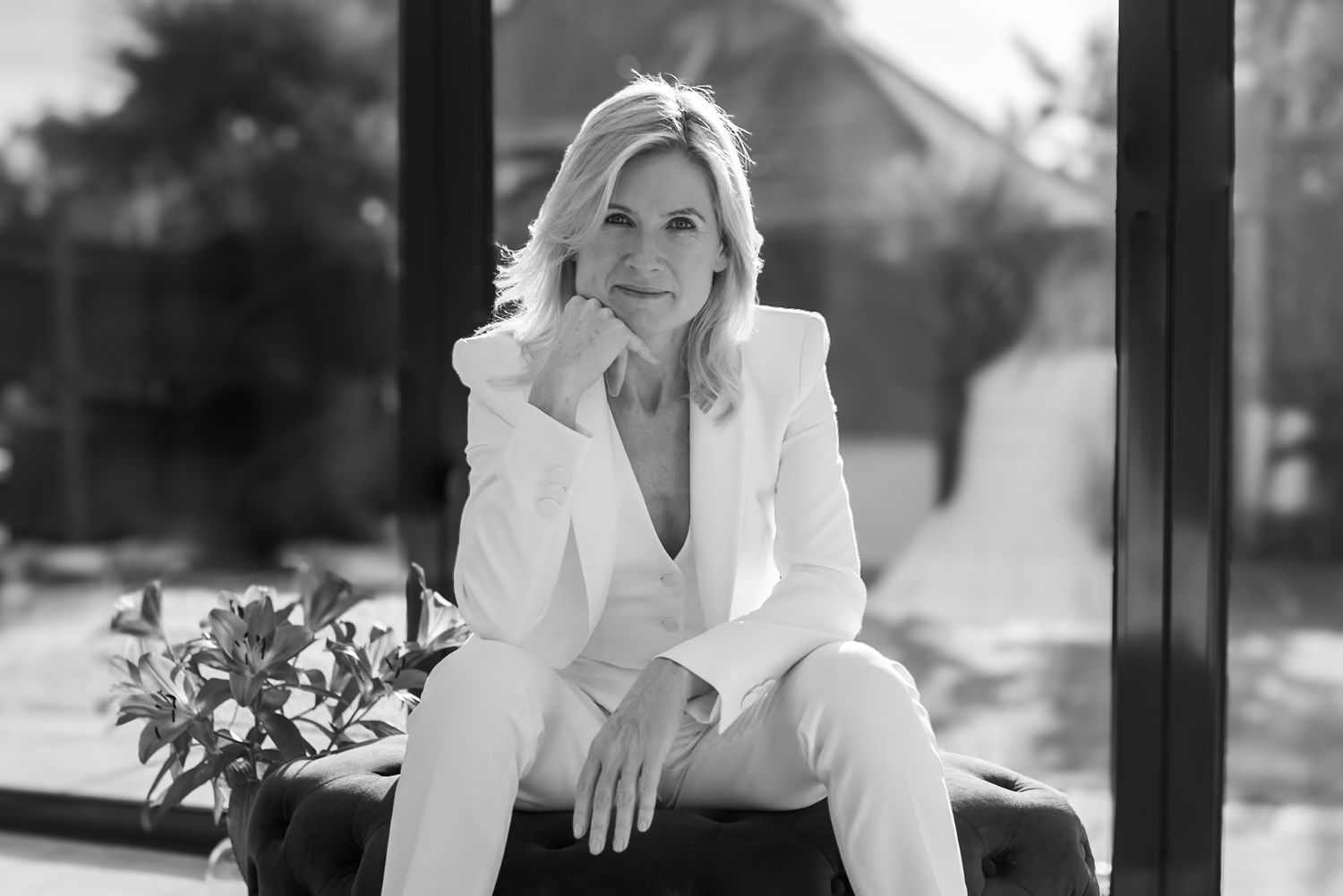Elegant woman in white suit seated confidently in black and white portrait photography outdoors.  Tara Lynn Coaching, Windsor. Business
