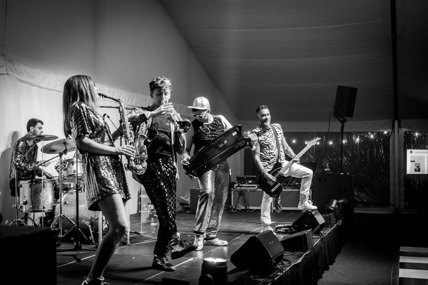 Black and white photo of a live band performing energetically on stage at an outdoor wedding reception.