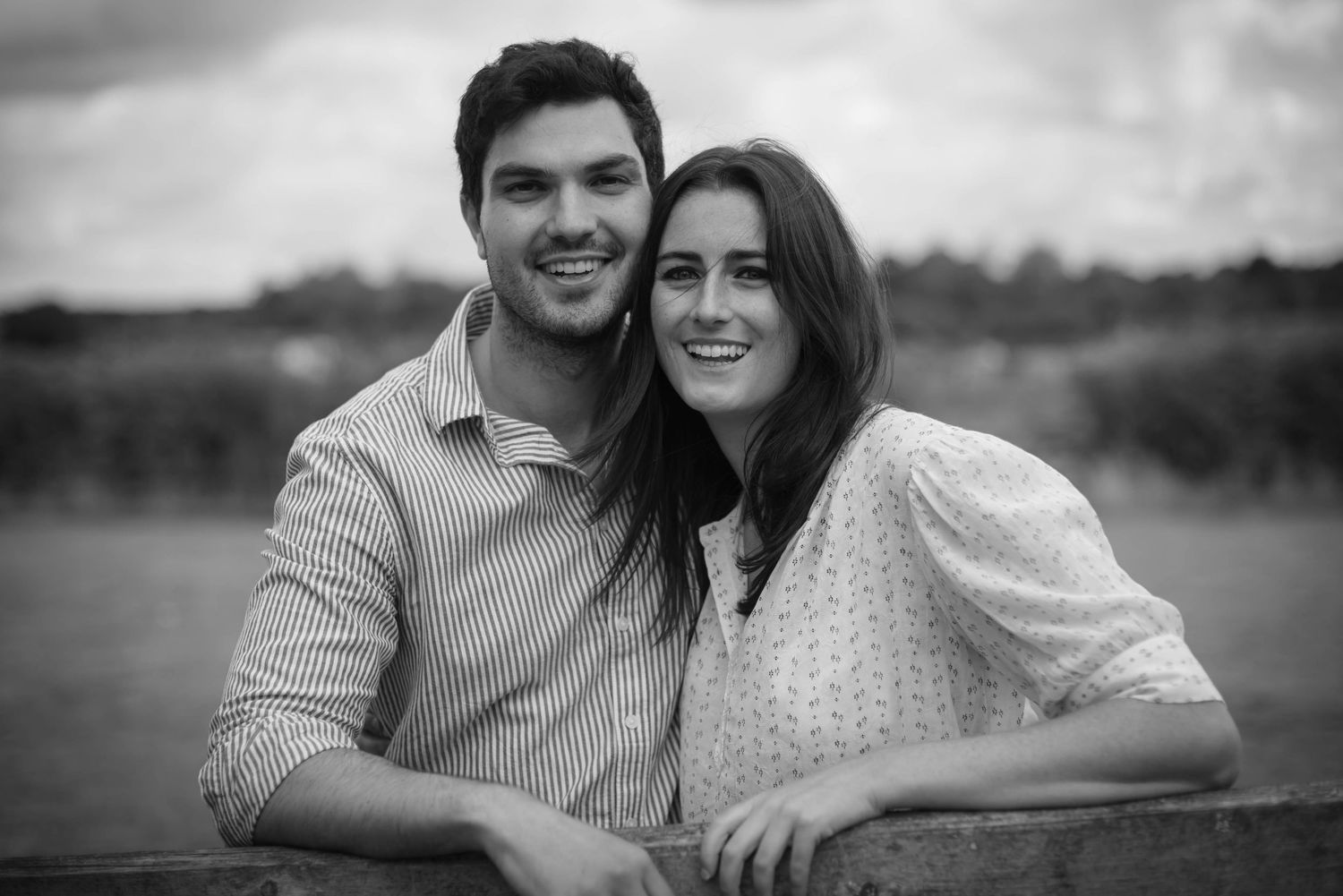 Young couple smiling together outdoors in black and white portrait photo.