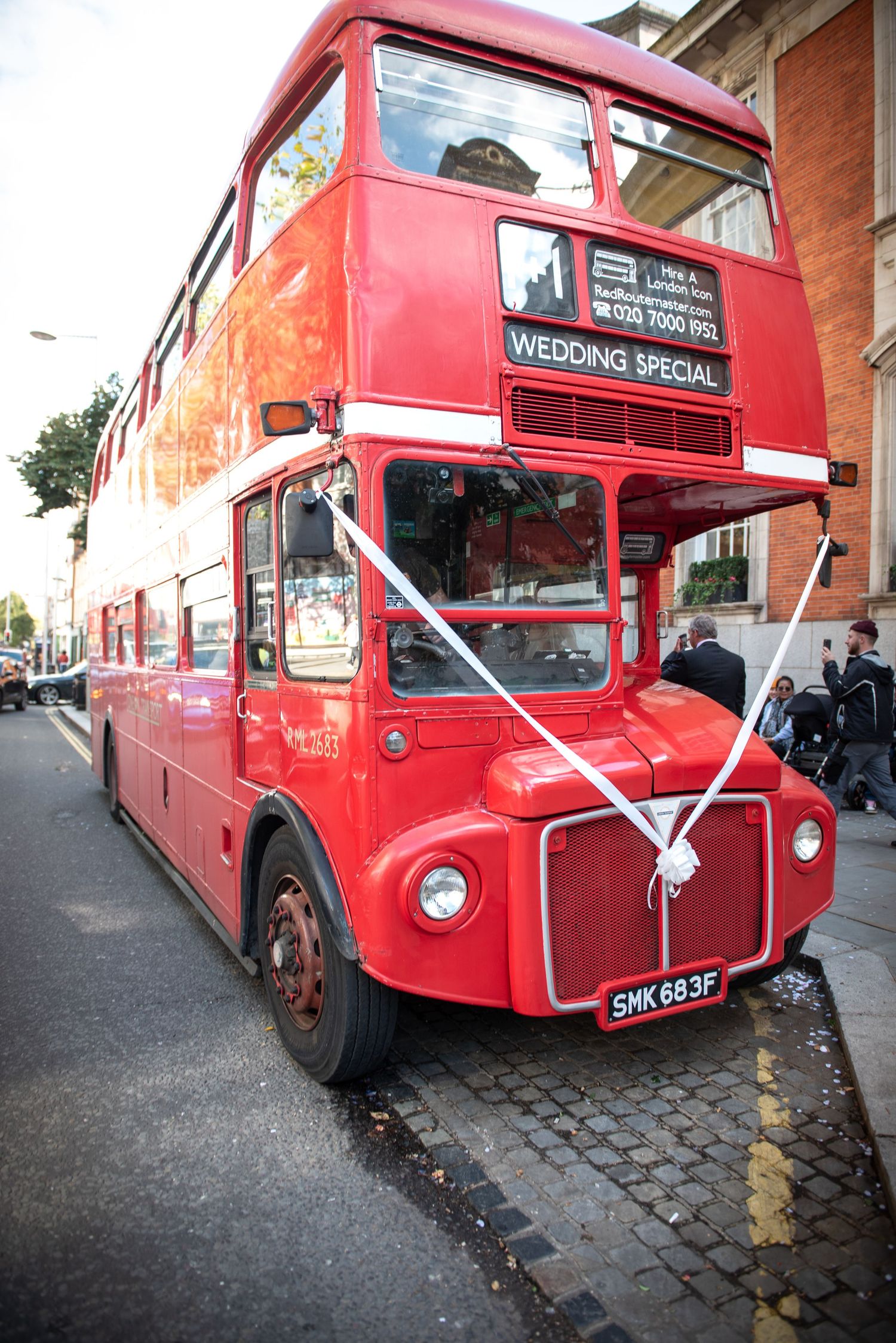 Vintage red London double-decker bus decorated with white ribbons displaying Wedding Special sign. Chelsea Town Hall Wedding, London