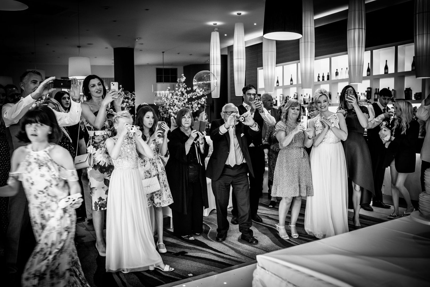 Wedding guests celebrate and cheer together in a black and white reception venue photo.