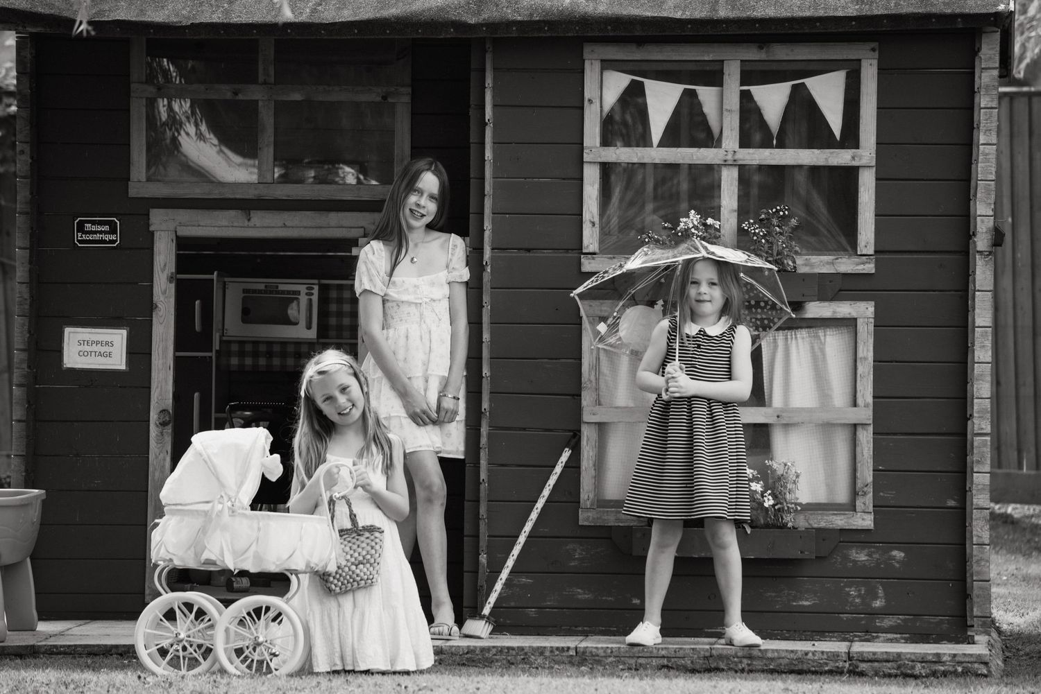 Black and white photo of two girls playing outside a rustic wooden building.