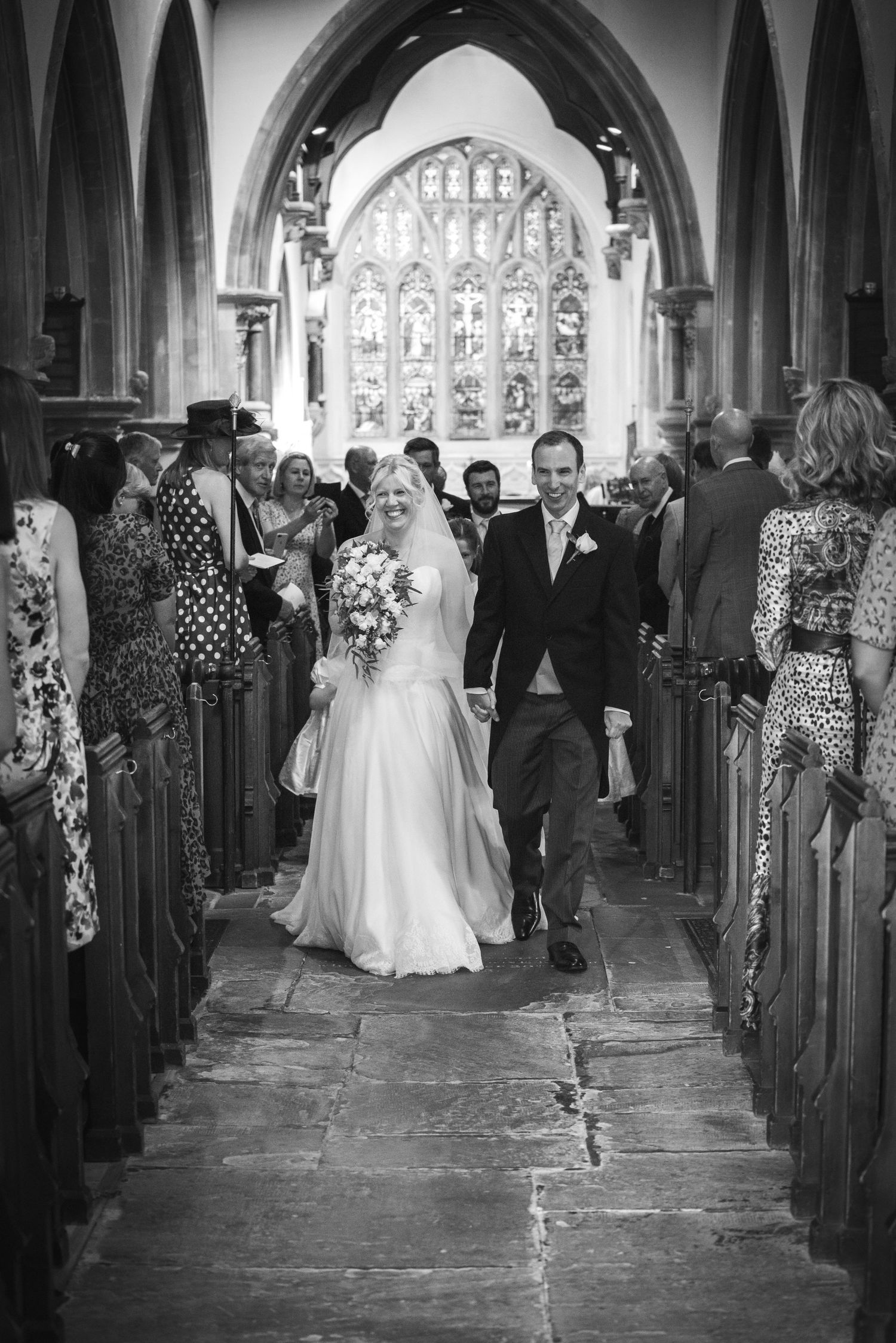 Bride and groom walking down the aisle of a historic church after their wedding ceremony. St Michaels Church Bray