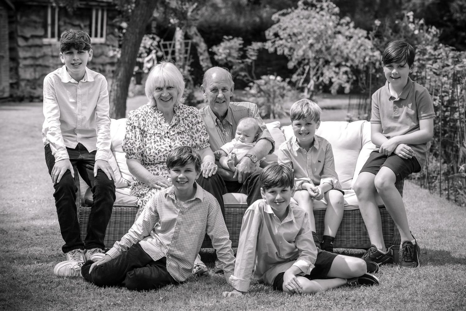 Black and white photo of grandparents surrounded by grandchildren in a garden.