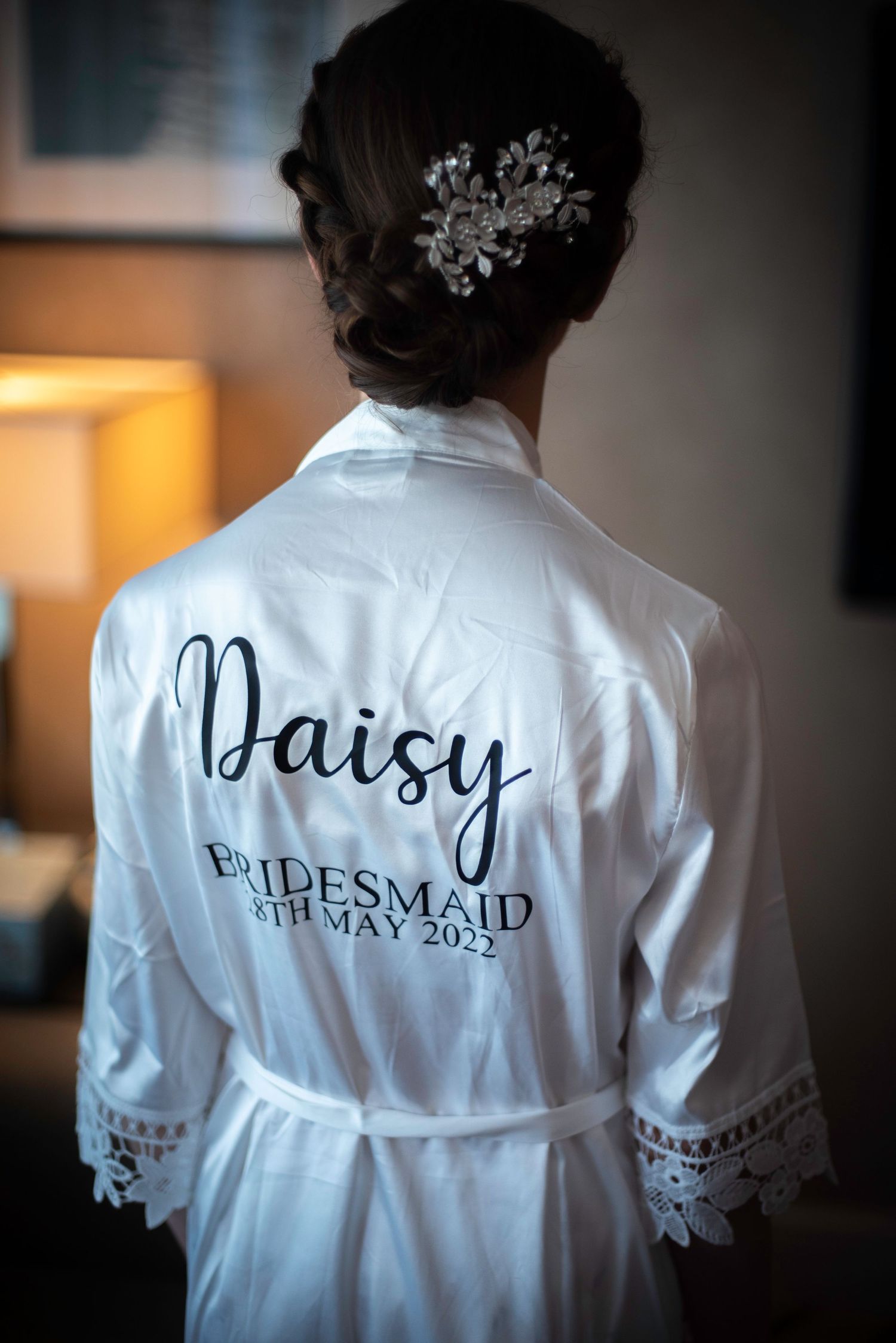 Personalized white satin bridesmaid robe with name Daisy and wedding date 8th May 2022 on back.