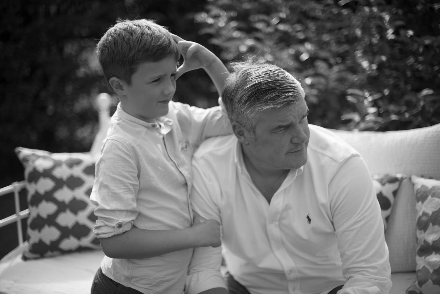 Black and white candid photo of a boy and older man relaxing outdoors.