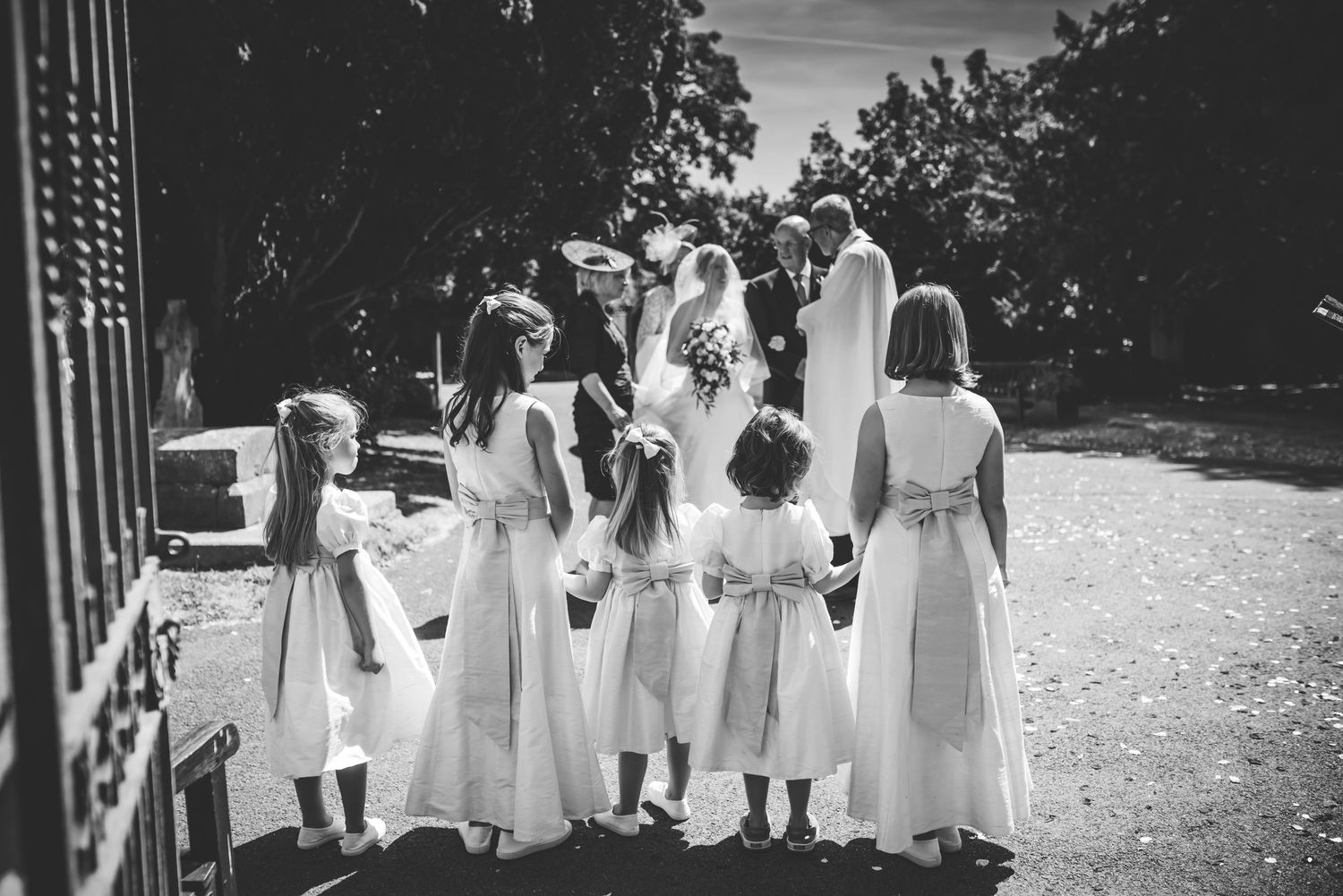 Black and white photo of bride with flower girls in white dresses gathered outside a church entrance. St Michaels Church, Bray