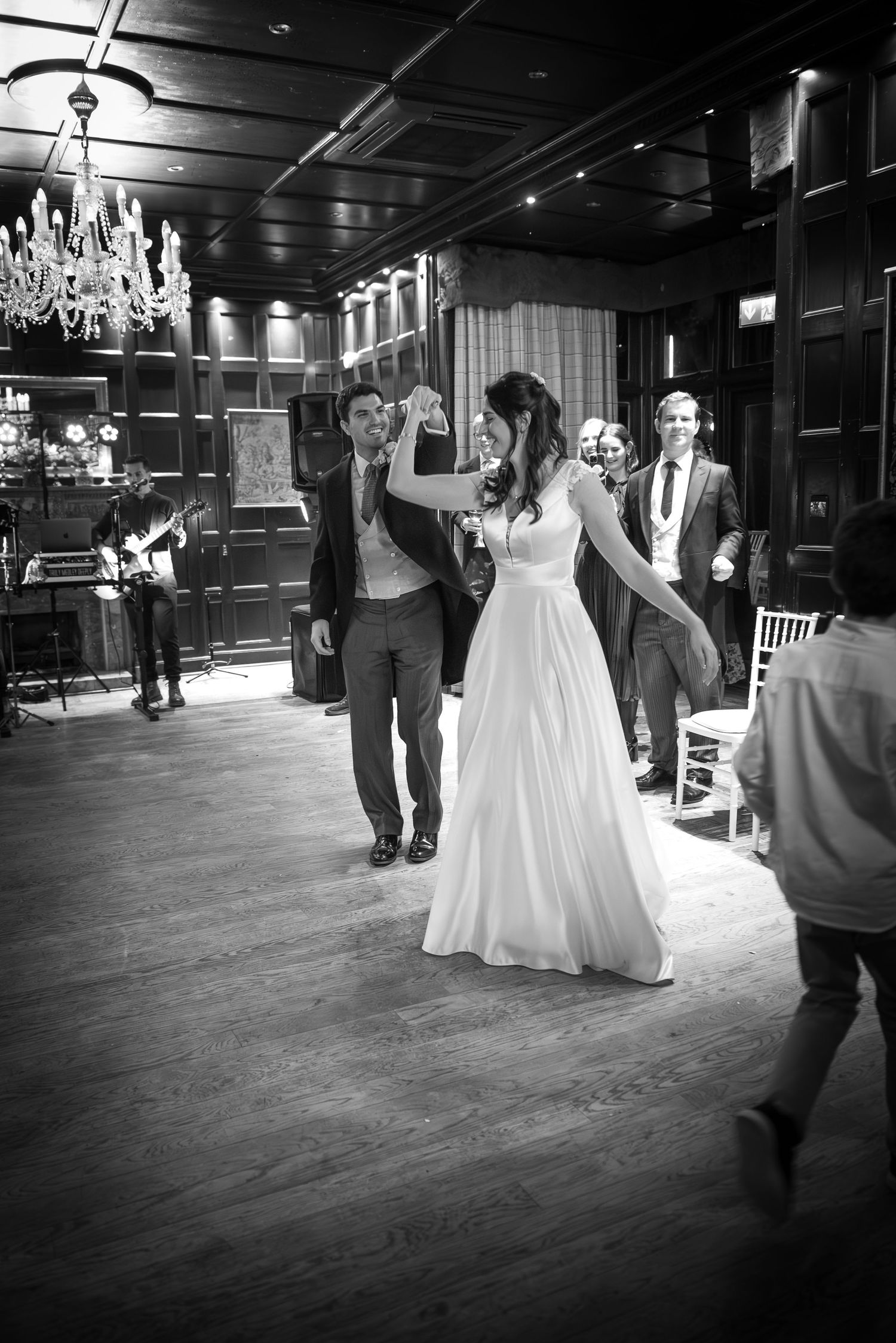Bride and groom sharing their first dance in a grand ballroom while guests watch and celebrate.