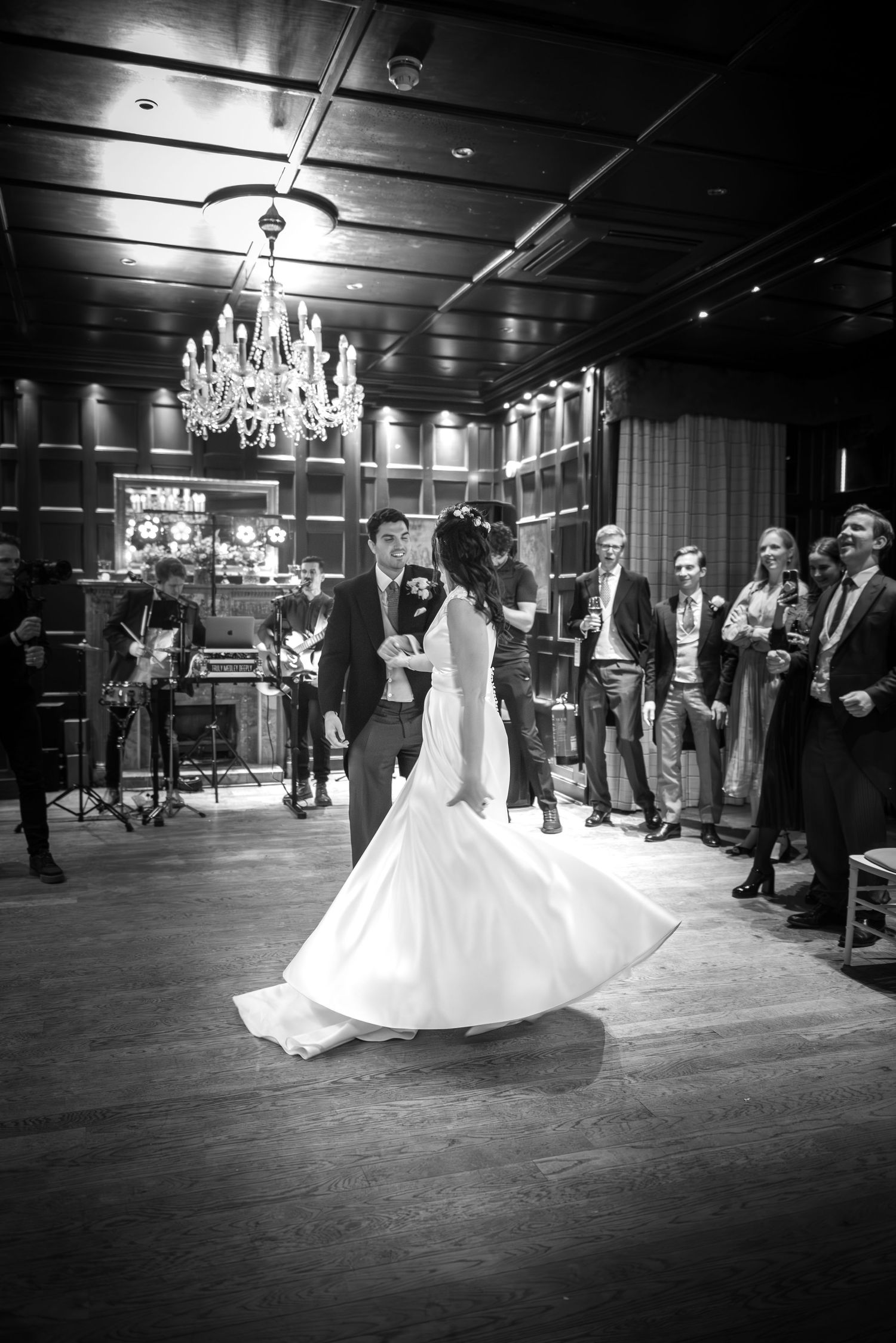 Bride twirling in her white gown during first dance as guests look on in a elegant ballroom.