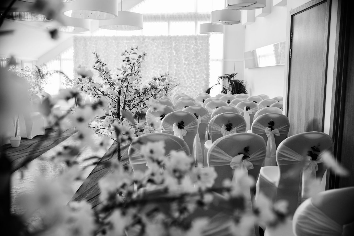 Black and white wedding ceremony venue with decorated chairs and floral arrangements.