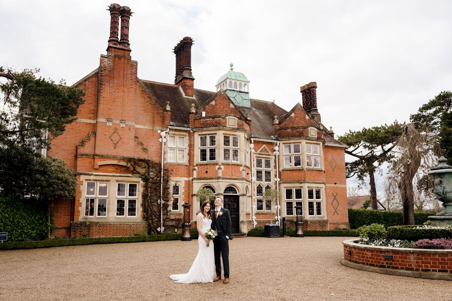 Bride and groom pose outside stunning red brick English manor house wedding venue.
