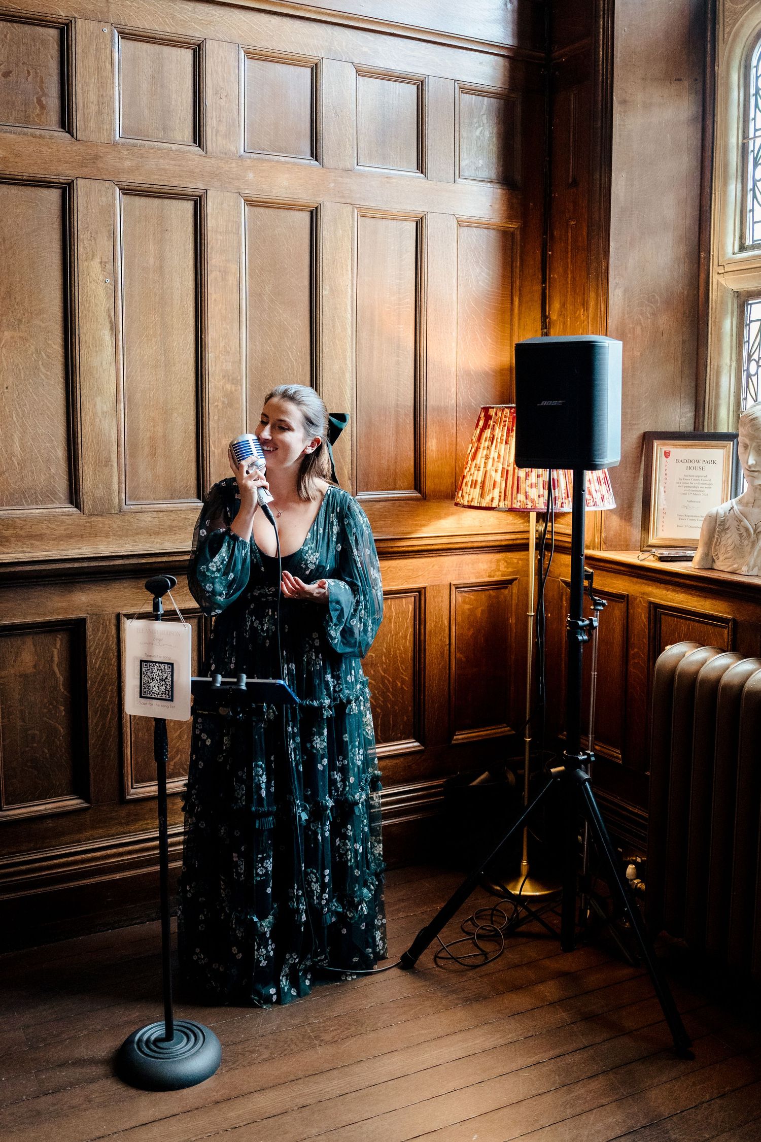 Female singer in green floral dress performing at wedding with vintage microphone.